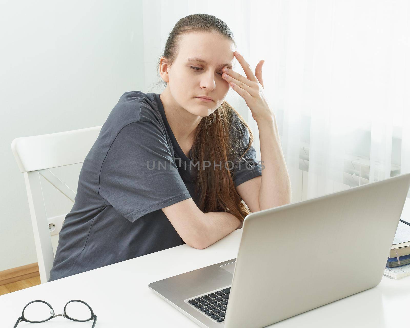 Girl rubs her eyes, her eyes are tired from the strain and hurt. Concept of harmful effects of the computer on vision. Distance education for students. Quarantine, self-isolation, socio phobia