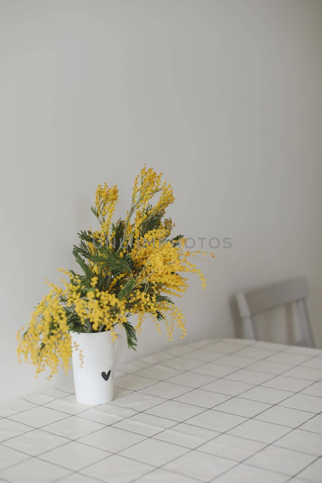 Mimosa branches in a glass vase on the table.