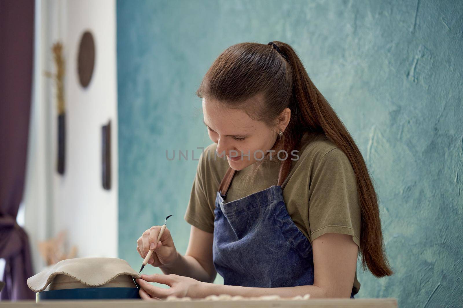 Woman making ceramic plate on workshop. Concept for woman in freelance, business. Handcraft product. Earn extra money, side hustle, turning hobbies into job.