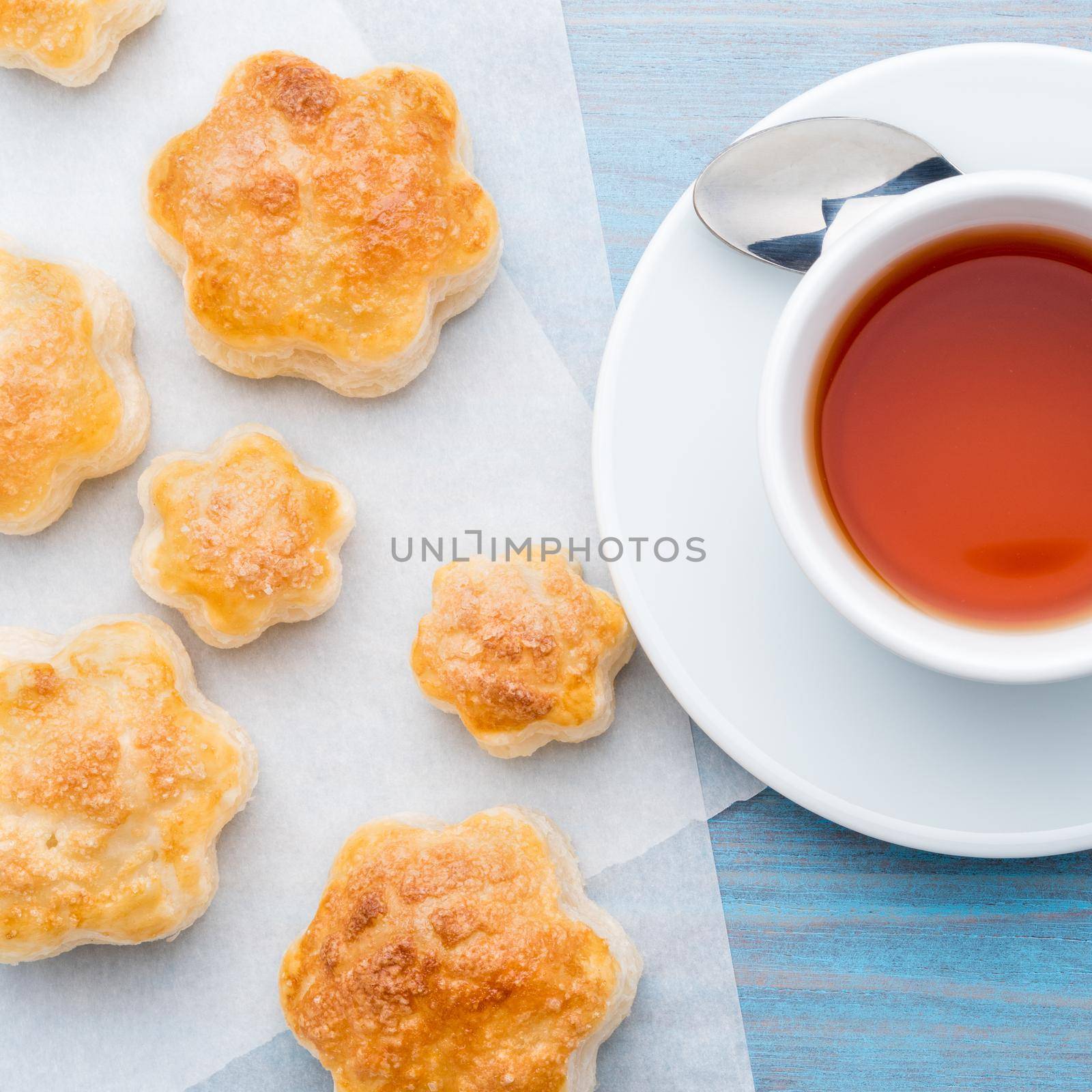 traditional breakfast with a cup of tea and sweet pastries - scones, a mug of tea, spoon, on wooden blue table, top view. by NataBene