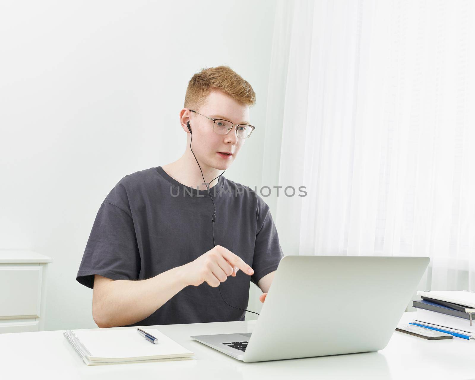 Distance learning or working. Quarantine, self-isolation, social phobia. Young boy speaking on online training, meeting, conference. Man looks at laptop. Freelancer, Concept Of Digital Nomad