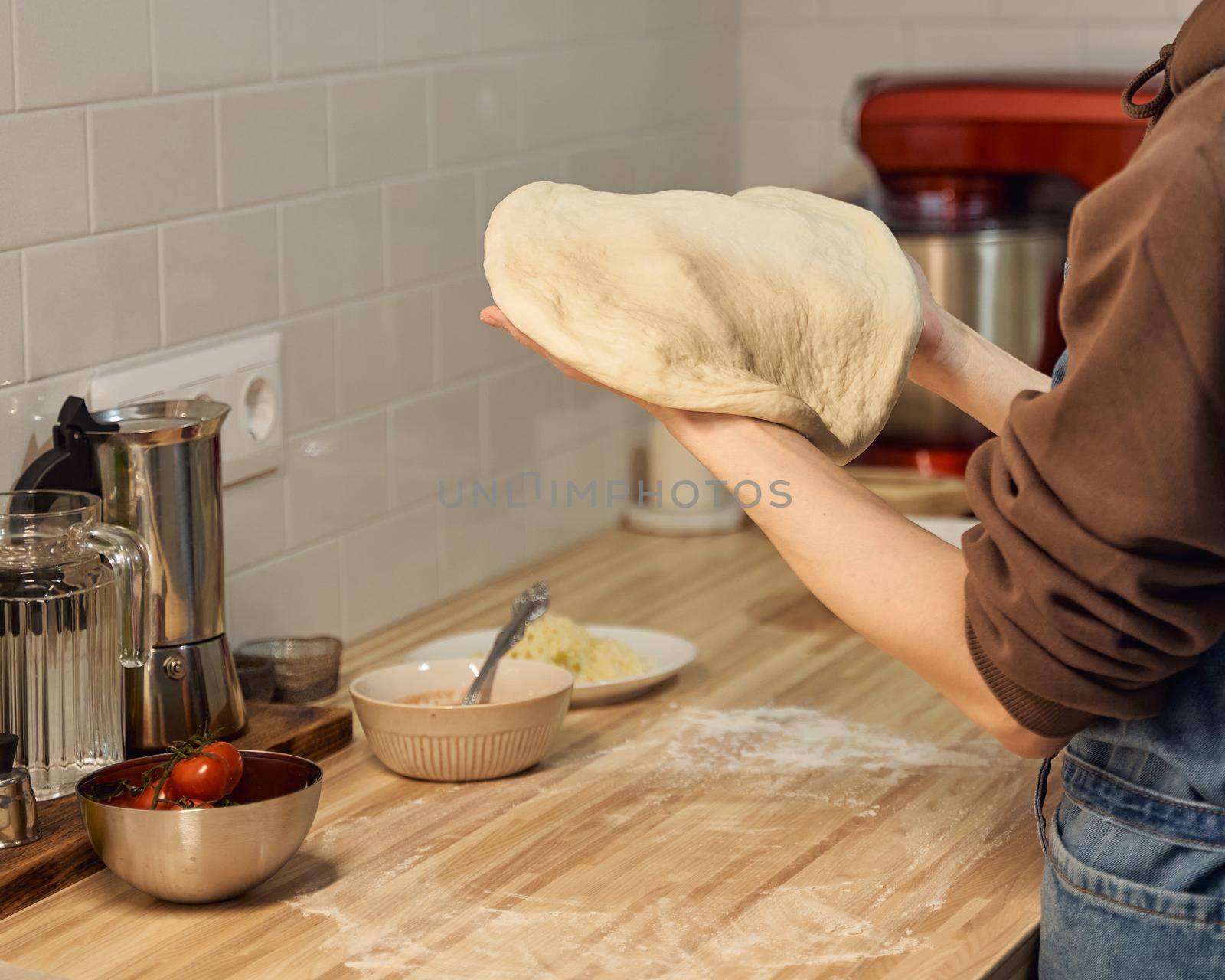 Faceless woman kneading dough on kitchen table at home, apartment. Homemade food by NataBene