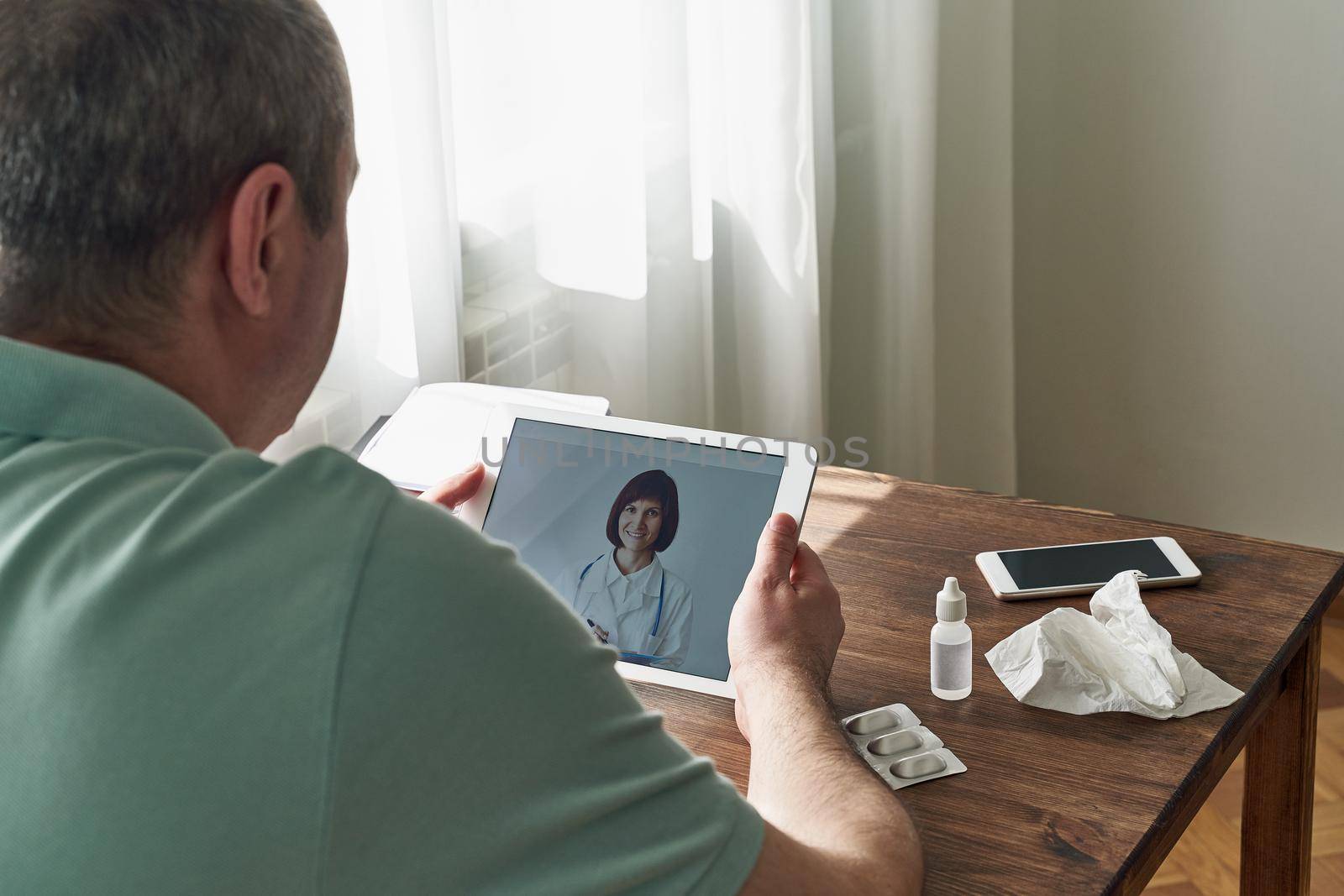Man looks at tablet, video call to doctor, communication with doctor online. Telemedicine. Treatment at home, consultation, examination
