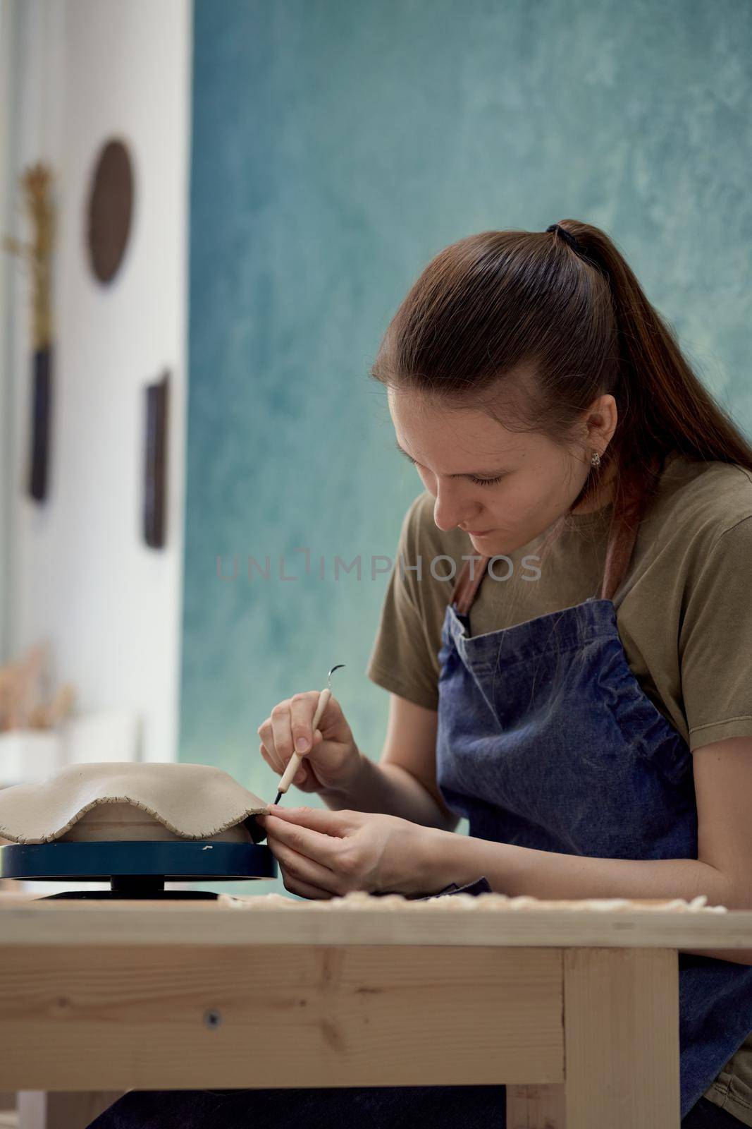 Woman making ceramic plate on workshop. Concept for woman in freelance, business. Handcraft product. Earn extra money, side hustle, turning hobbies into job. Vertical