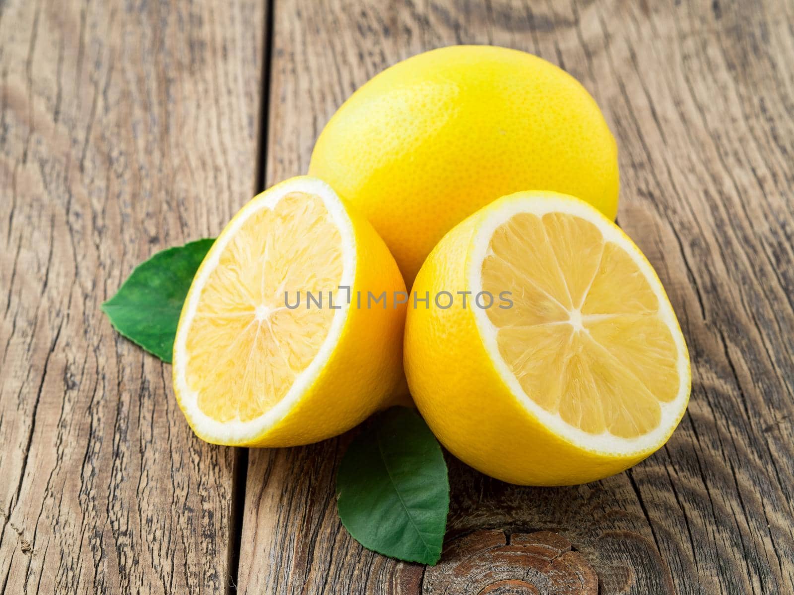 fresh lemon and cut off half on wooden old table, side view by NataBene