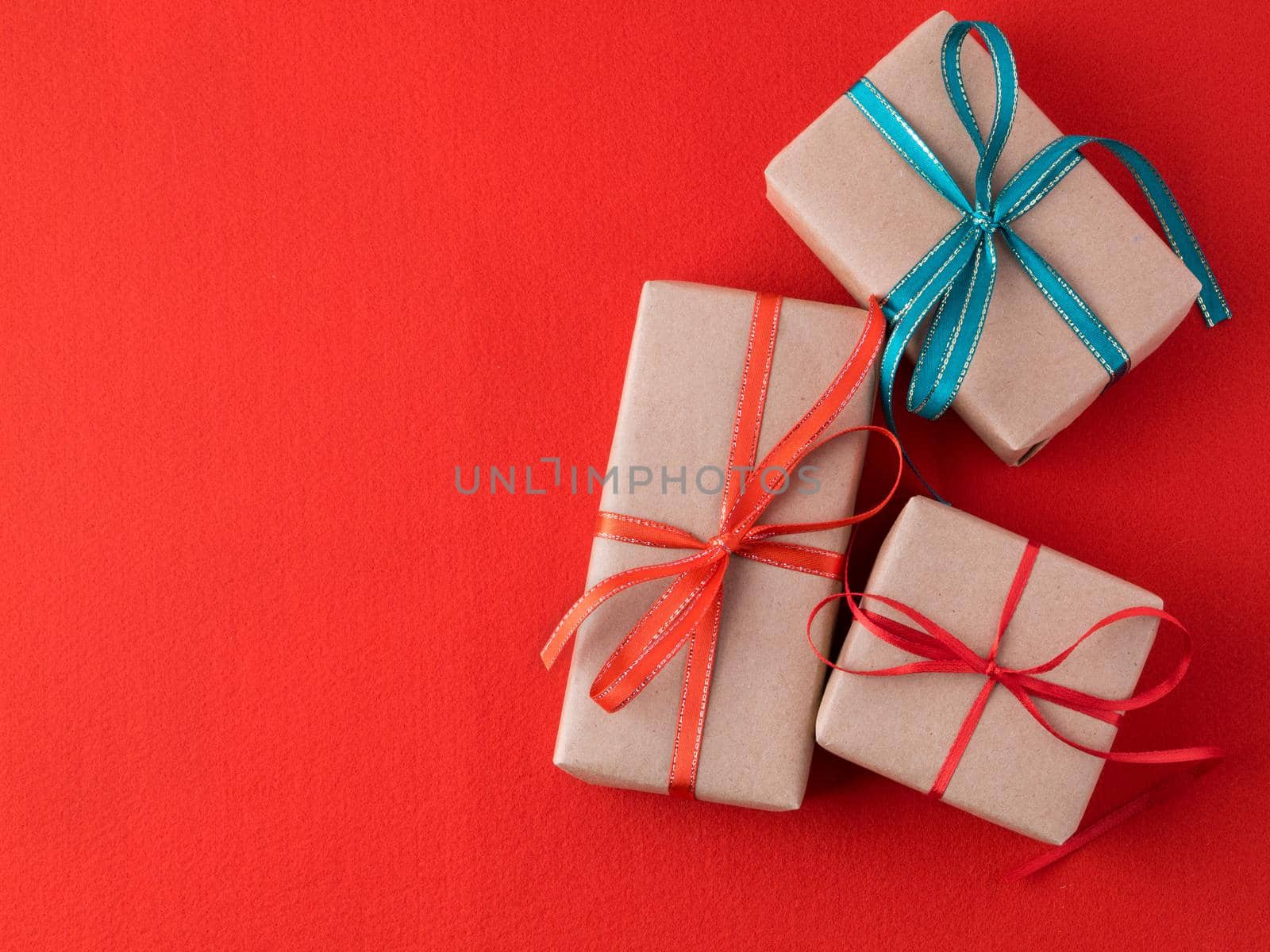 Background for Valentine's Day, birthday, holiday, shopping. Gifts from the store in a pack of Kraft brown paper with red ribbons on a bright red background