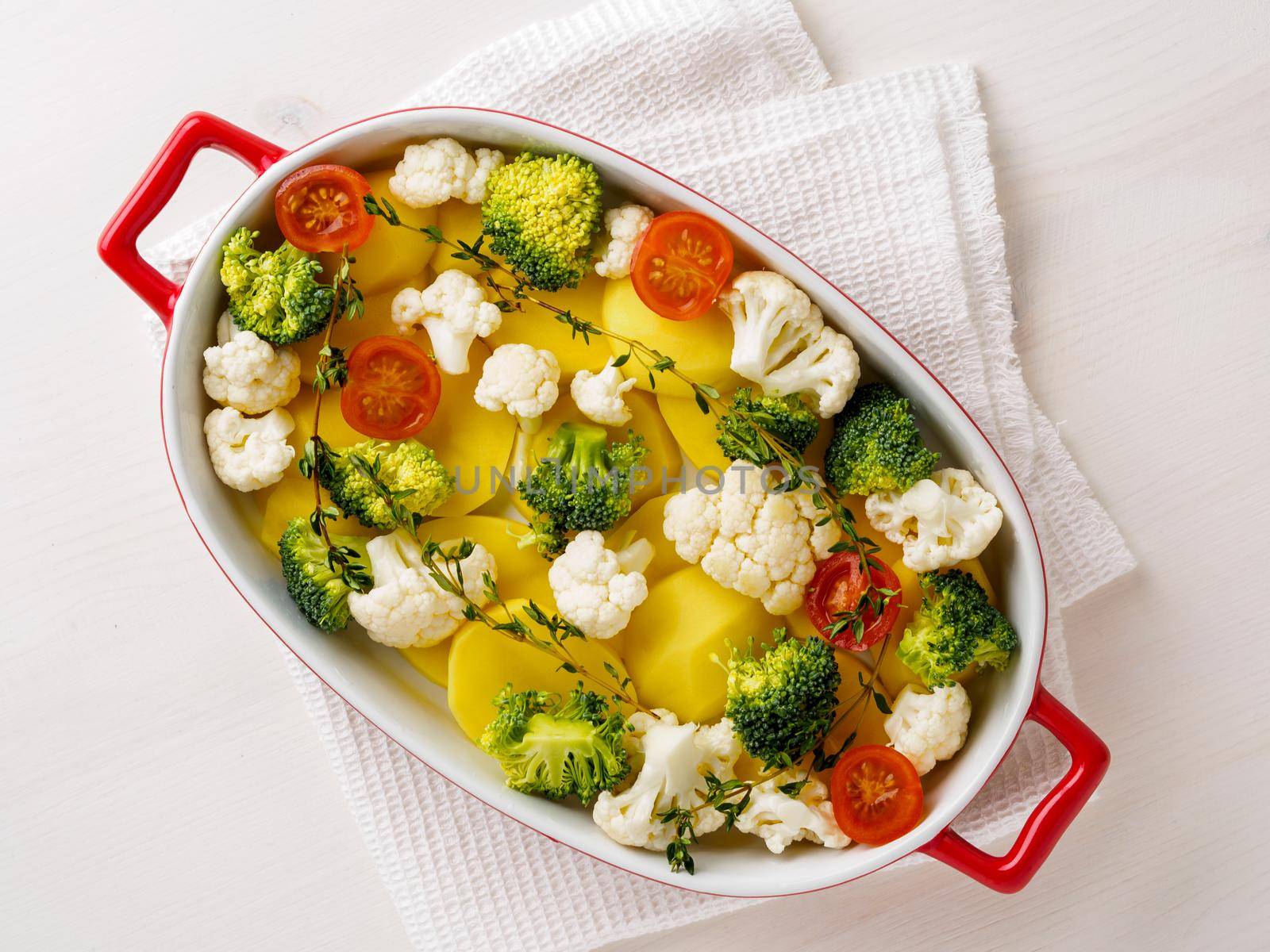 Dietary vegetarian dish of raw mixed vegetables - potatoes, cauliflower, broccoli, tomatoes, thyme, seasonings. Healthy diet. Top view, empty space for the test. by NataBene