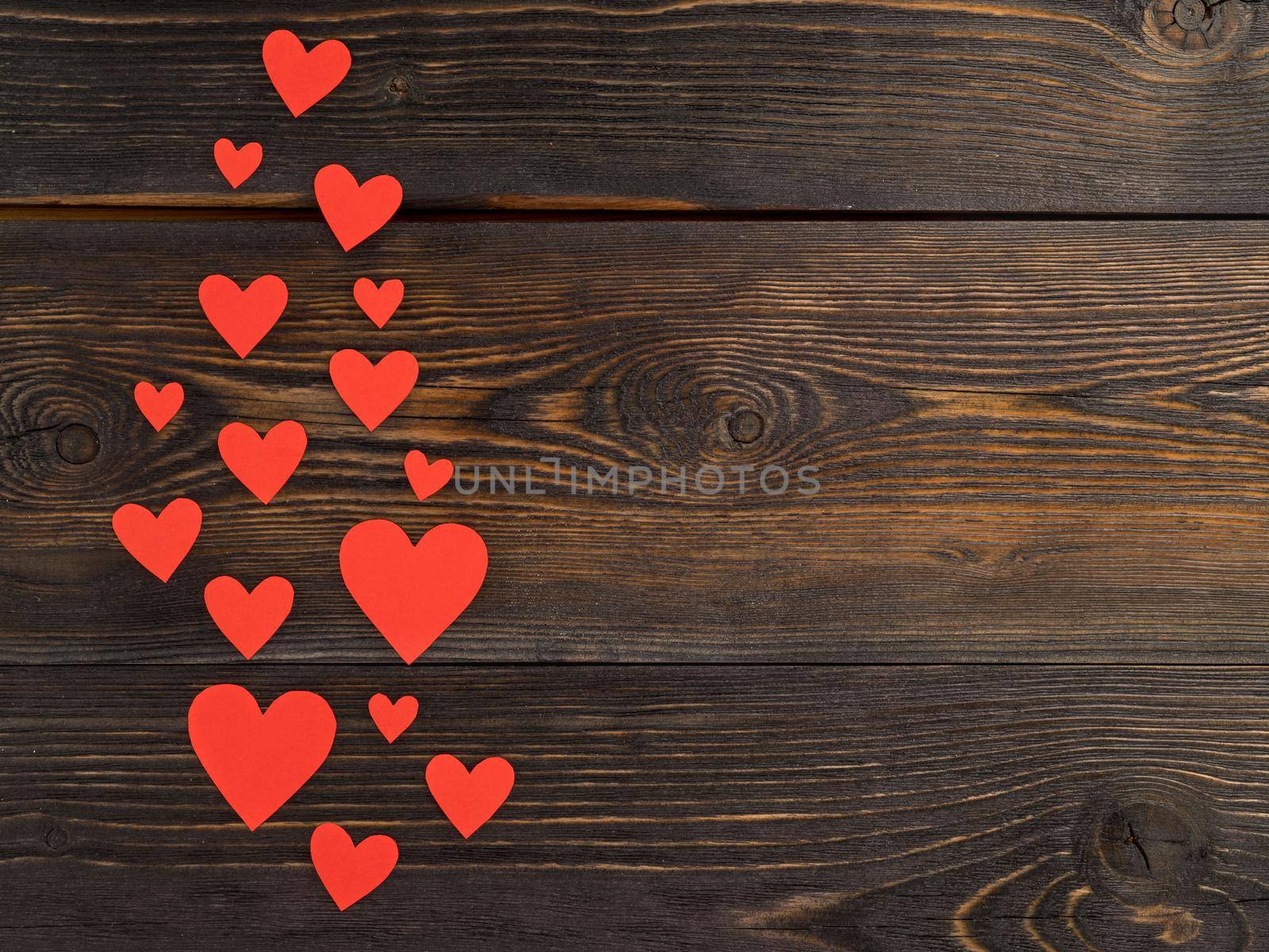 Lots of red paper hearts on a dark brown rustic weathered wooden background, top view by NataBene