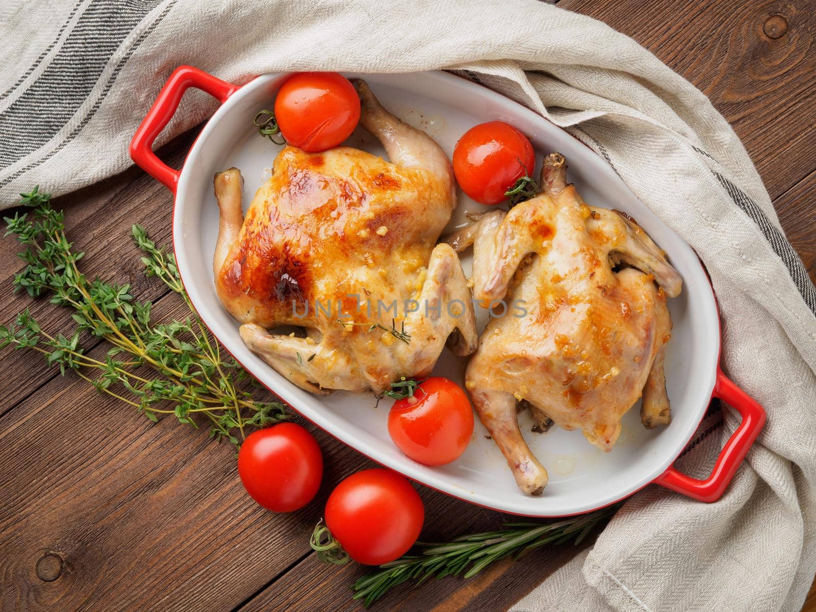 two carcasses fried chicken in a bowl, baked chucks in an oven with tomatoes, with crispy crust, on dark brown wooden rustic table, top view by NataBene