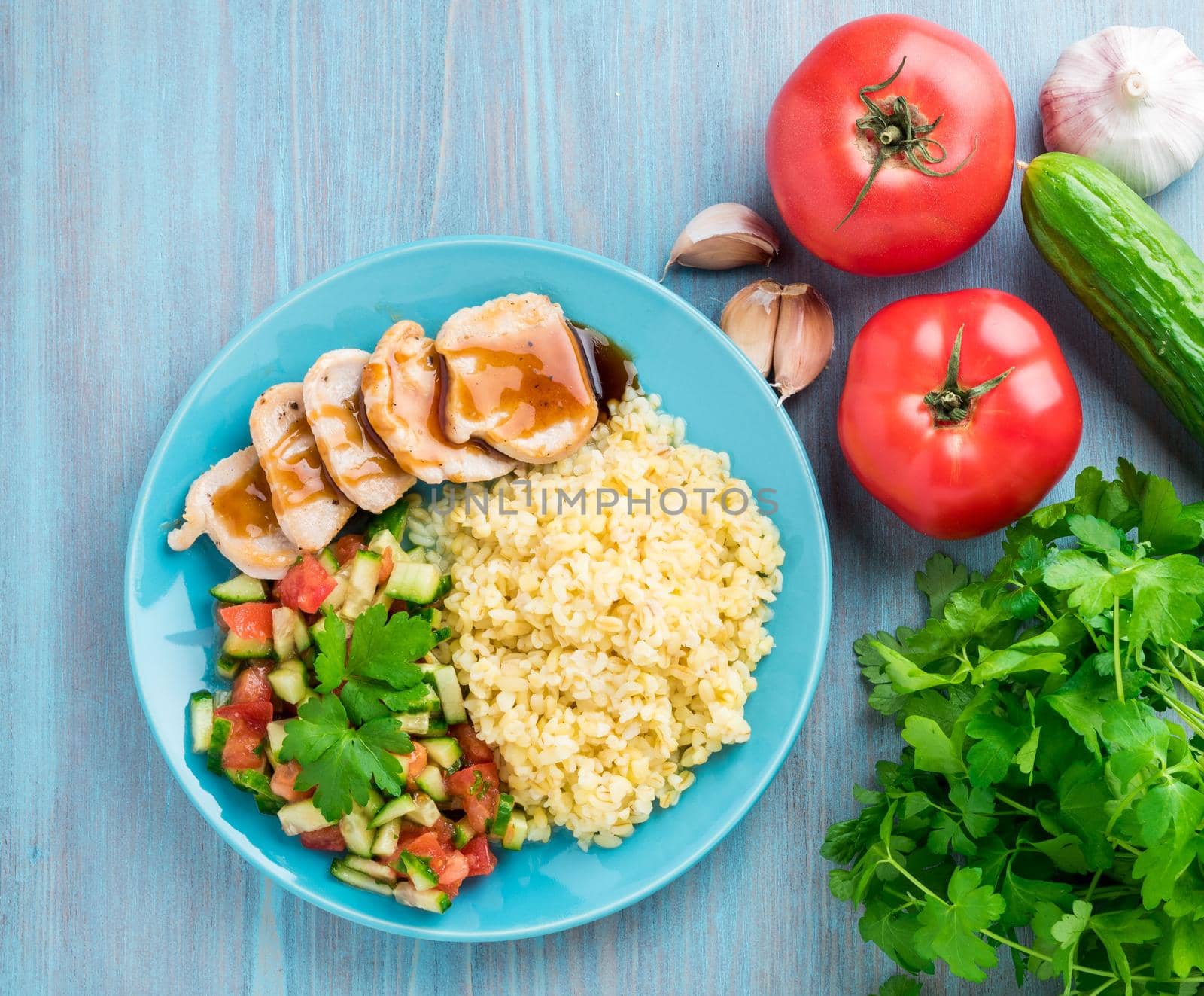 Turkey meat, fried with teriyaki sauce, cucumber salad tomato, vegetables, a side dish of bulgur, top view