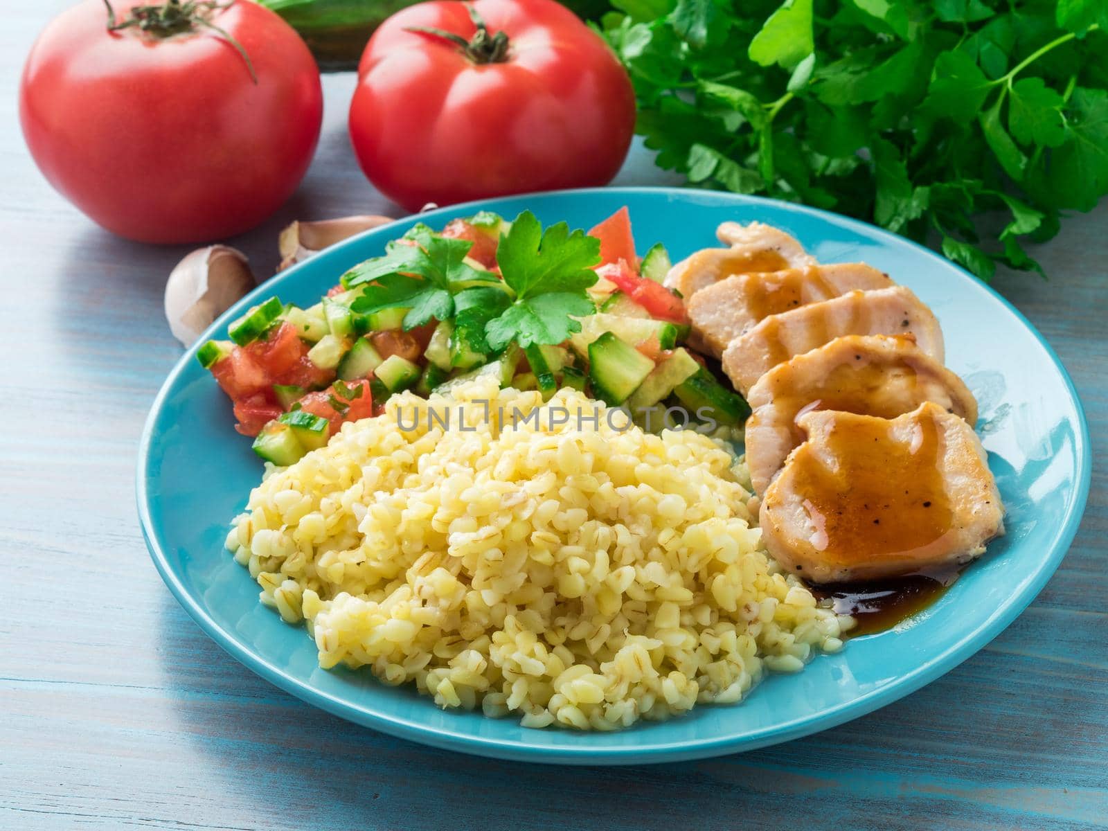 Turkey meat, fried with teriyaki sauce, cucumber salad tomato, vegetables, a side dish of bulgur, side view by NataBene