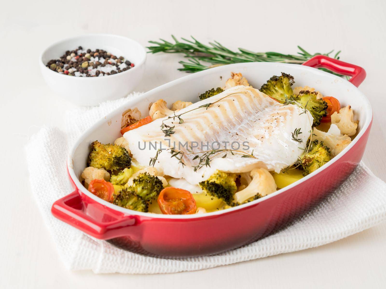 Fish cod baked in the oven with vegetables - healthy diet healthy food. Light white wooden background, side view.