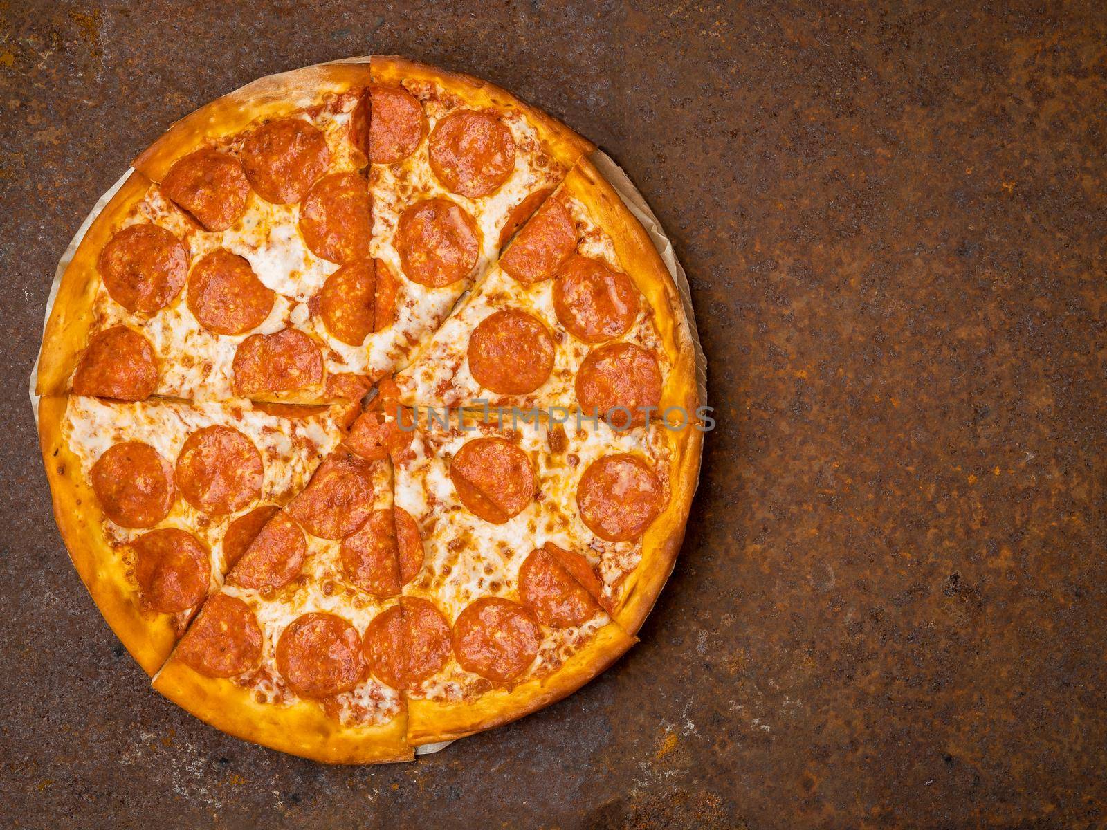 round Italian pizza pepperoni on a rusty metal desk top view, empty space for text.