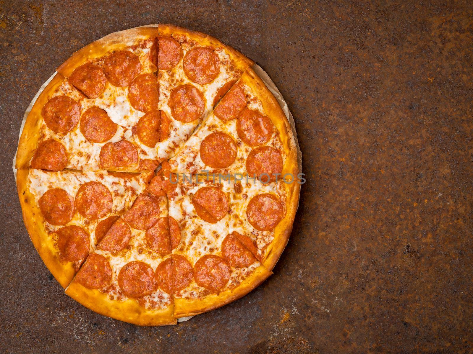 round Italian pizza pepperoni on a rusty metal desk top view, empty space for text.