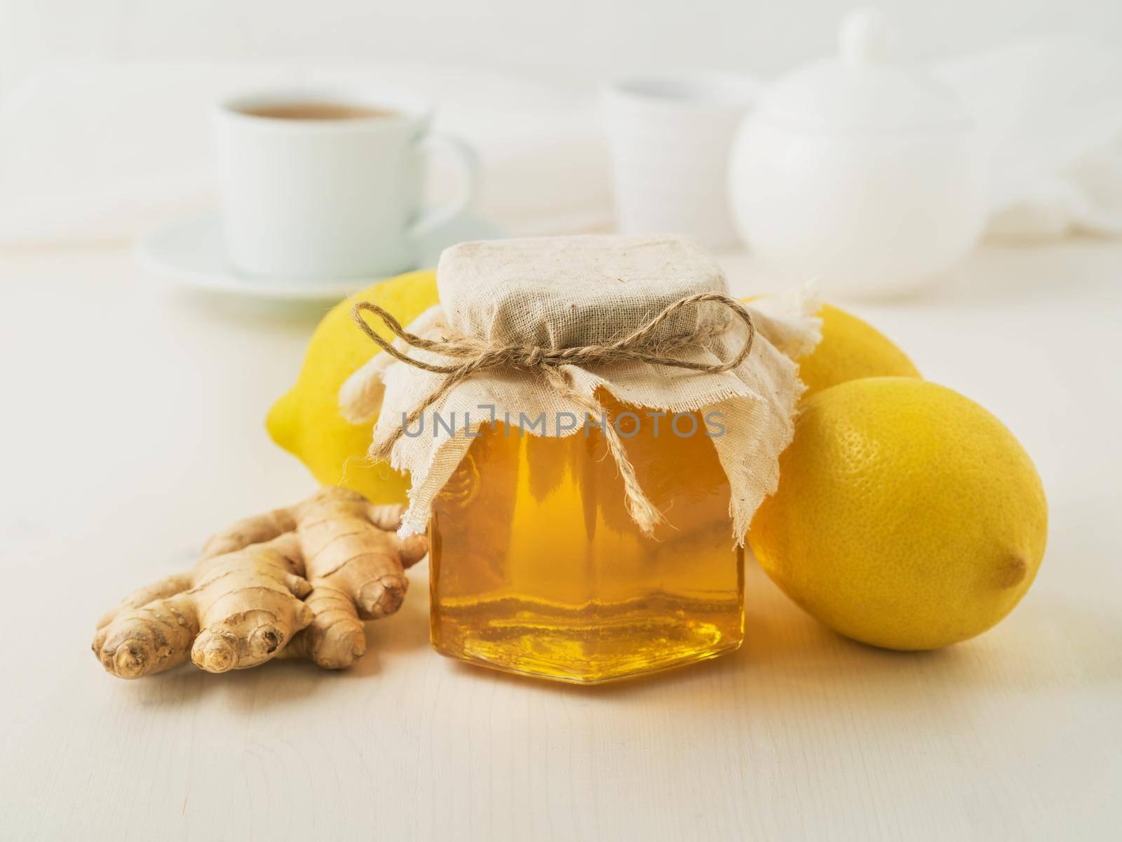 Popular ways to treat a cold - a jar of honey, ginger, lemons on white background, side view