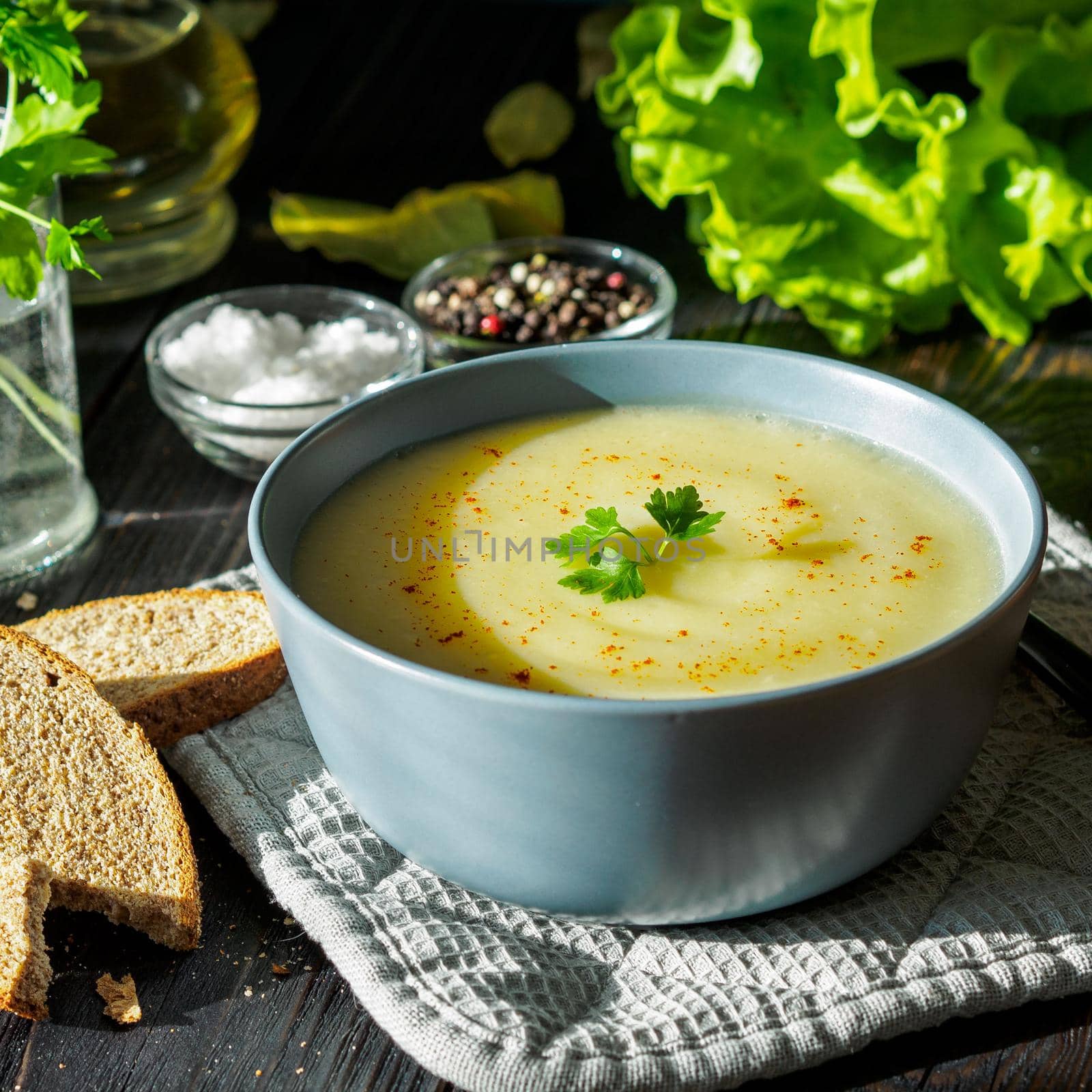 Dietary vegetarian cream soup puree, with potatoes and cauliflower, on a dark brown-blue wooden table, side view, close up by NataBene