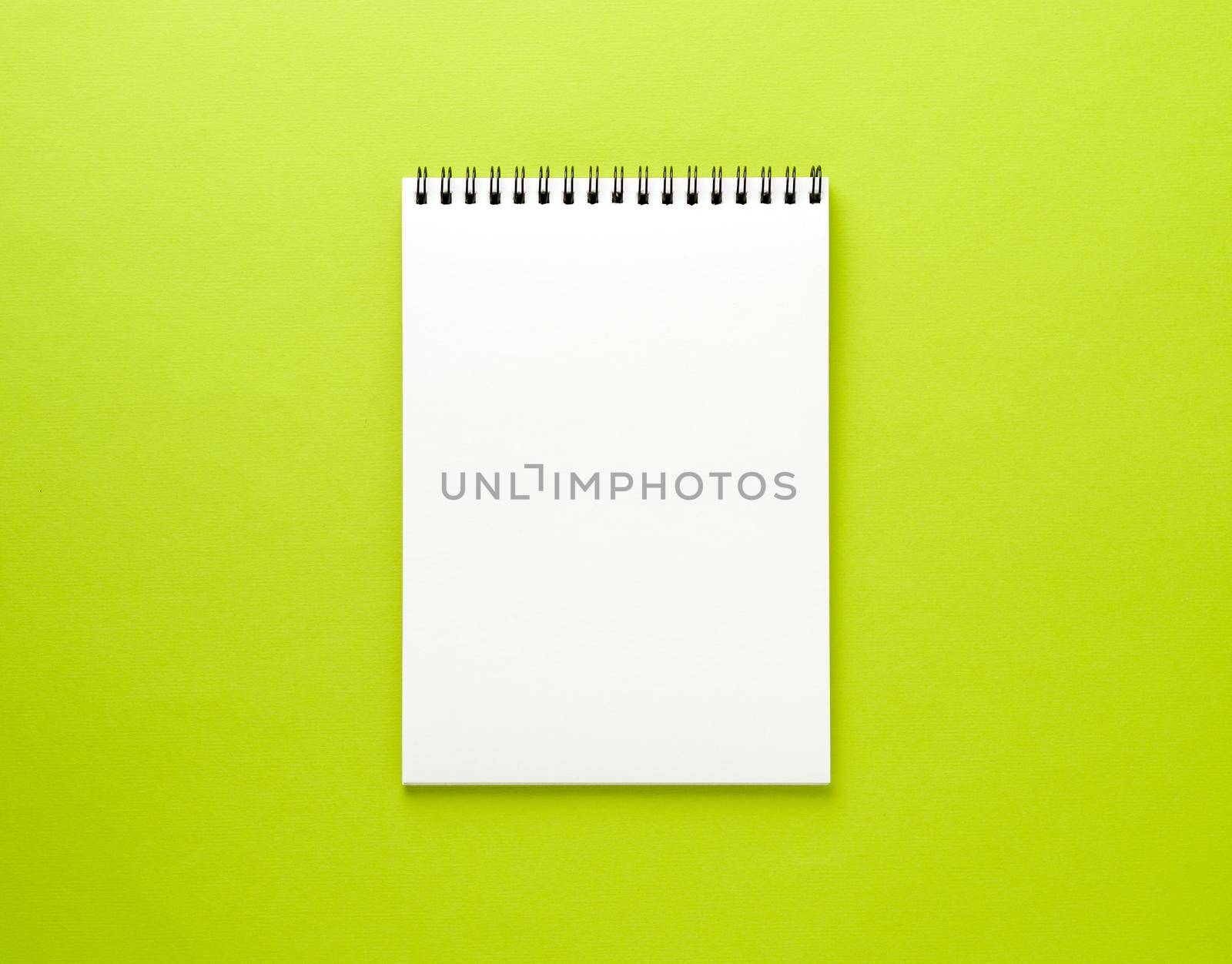 Blank notepad white page on green desk, color background. Top view, empty space for text.