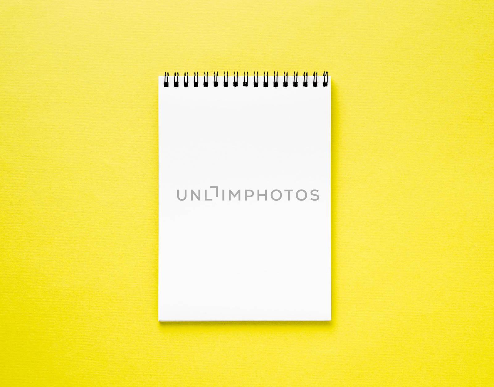 Blank notepad white page on yellow desk, color background. Top view, empty space for text.