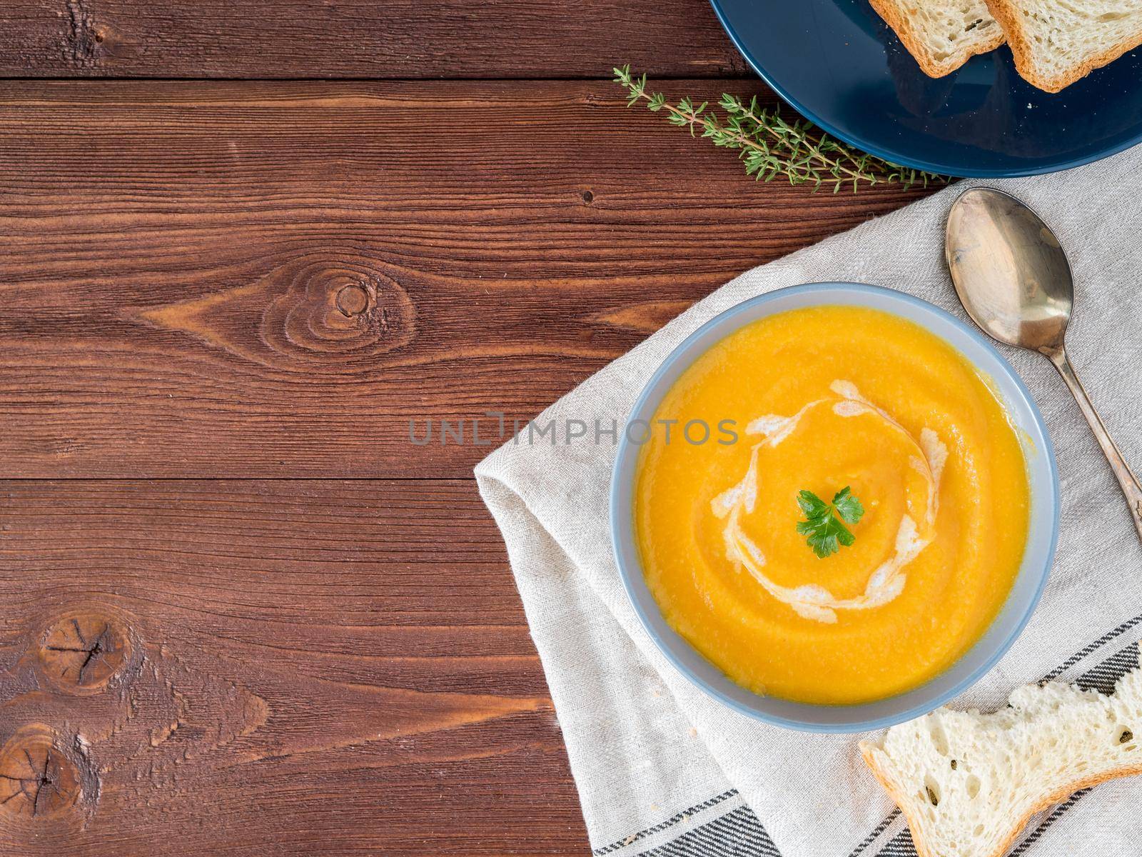 Dietary vegetarian pupmkin cream soup puree, on dark brown wooden table, top view, copy space, close up. by NataBene