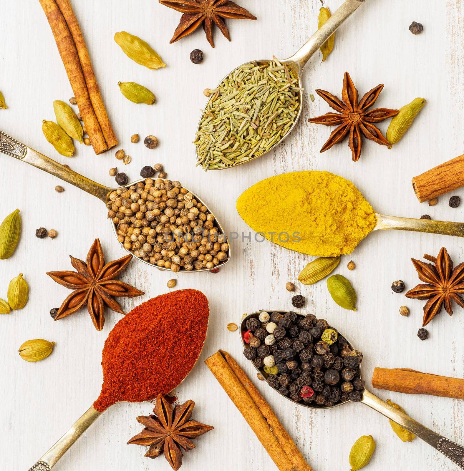 Mix of Indian spices in spoons on white wooden table, top view. Background with seasonings by NataBene