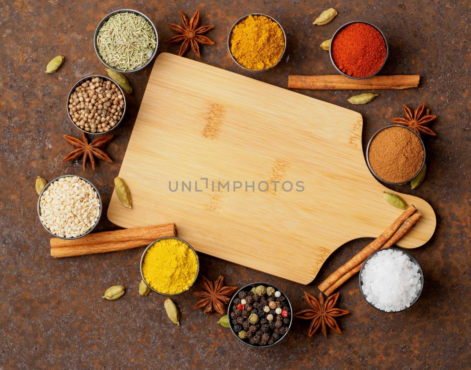 Various Indian spices in metal cups. Empty wooden Board, top view, space for text. by NataBene