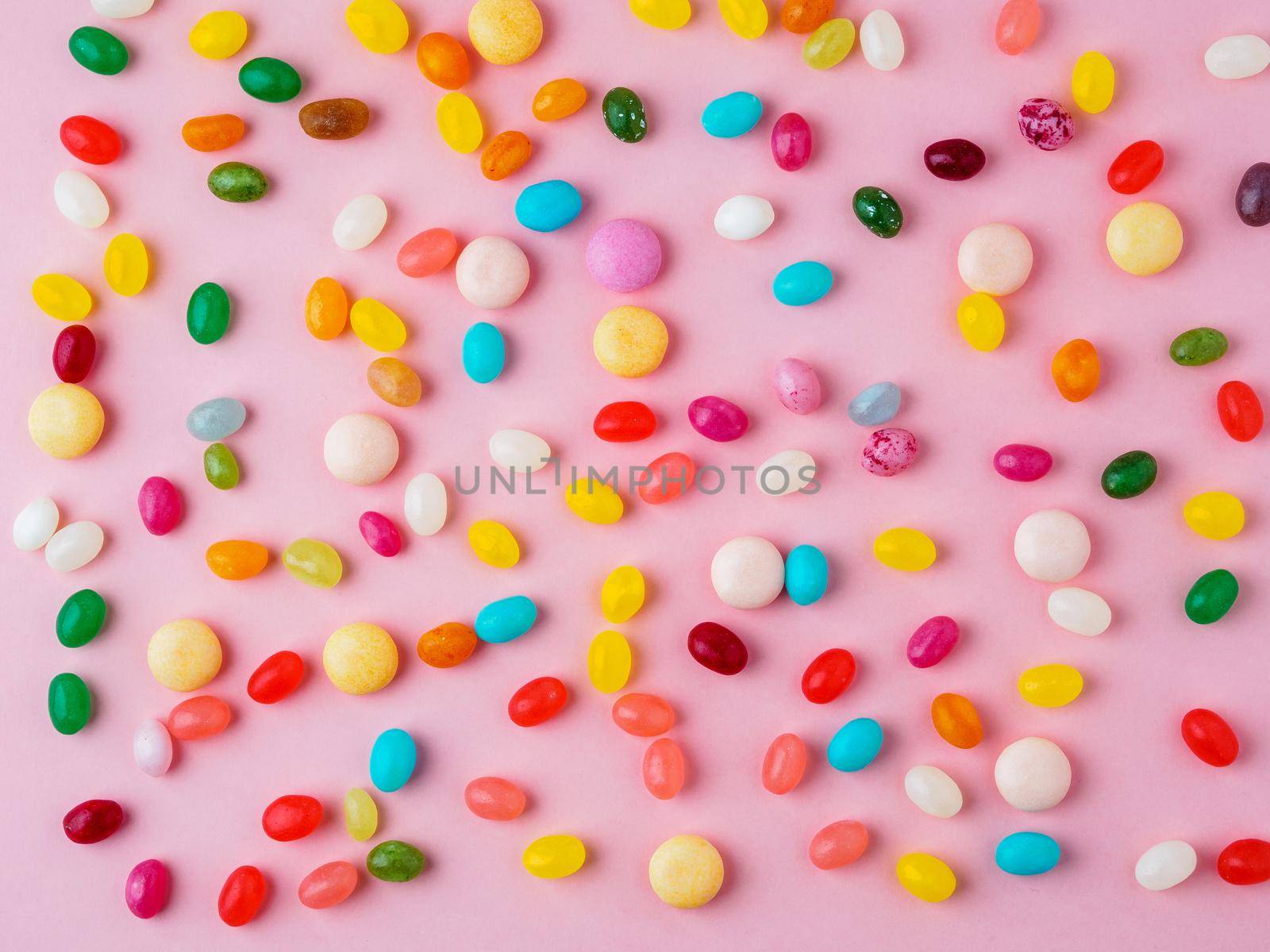Many scattered colorful sweets, candies, lollipops on bright pink background, top view by NataBene