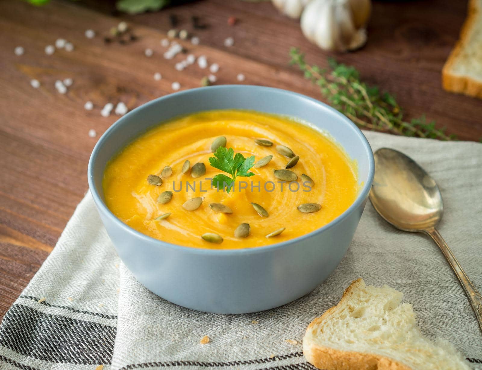 Dietary vegetarian pupmkin cream soup puree, on dark brown wooden table, side view, close up. by NataBene