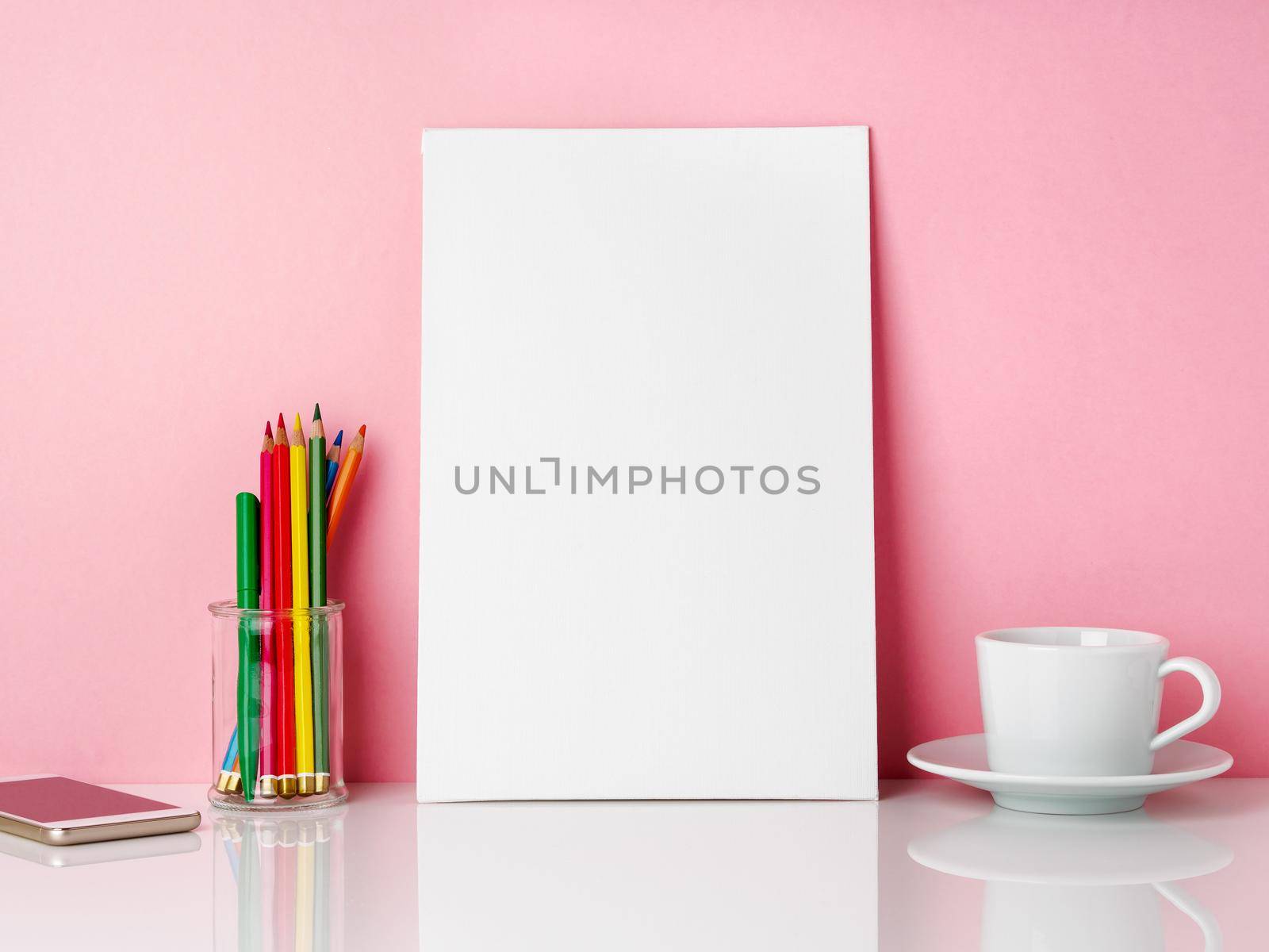 Blank white frame and crayon in jar, cup of coffee r tea on a white table against the pink wall with copy space by NataBene