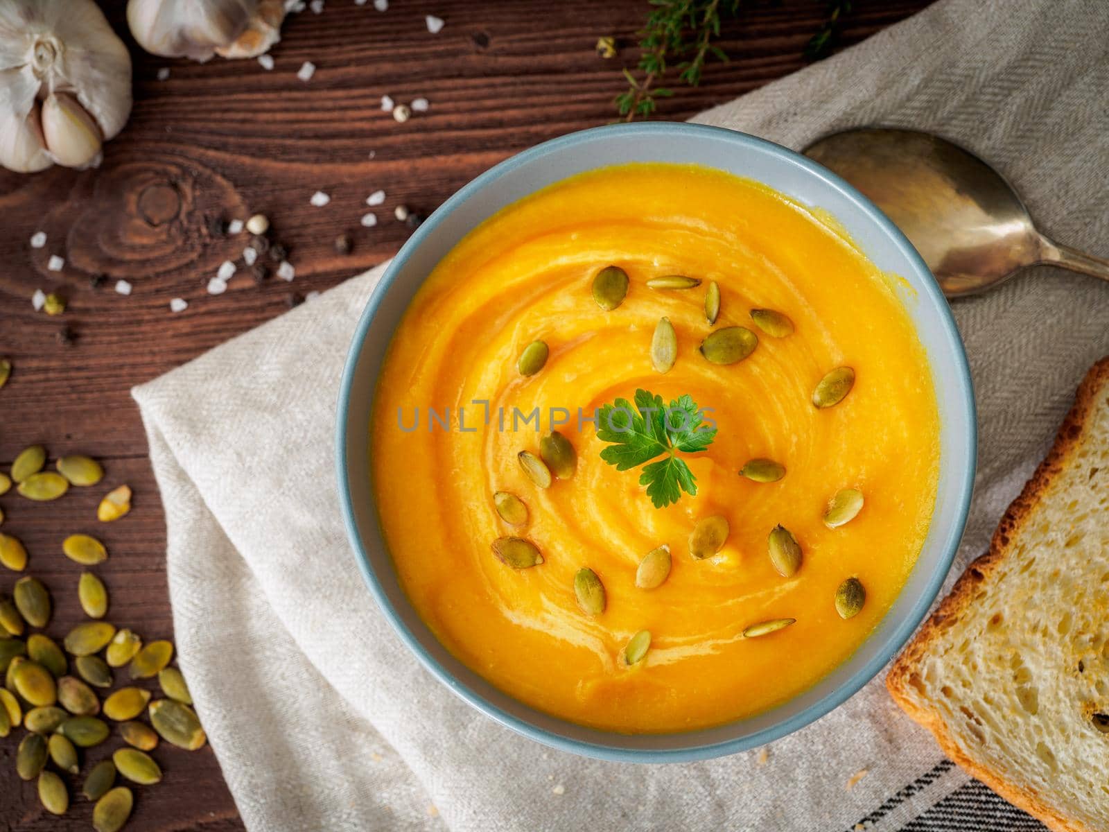 Dietary vegetarian pupmkin cream soup puree, on dark brown wooden table, top view, close up.