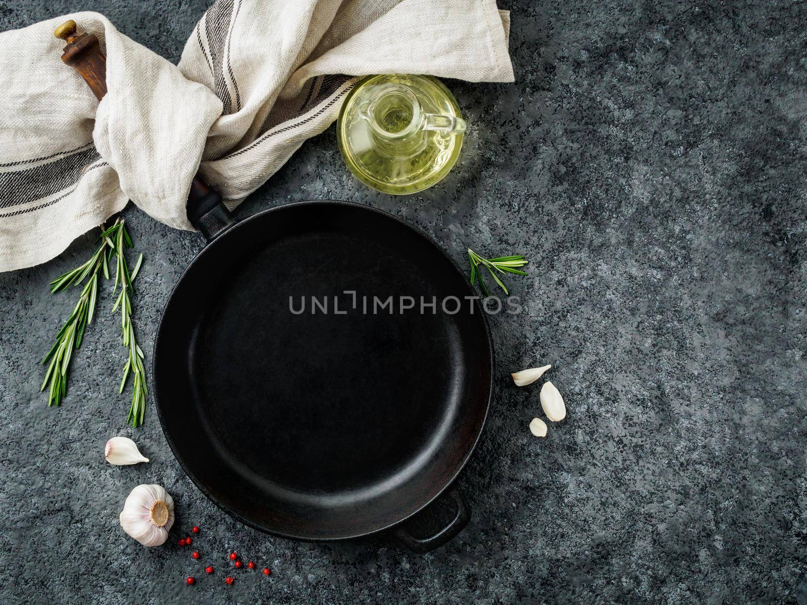 blank cast iron frying pan on dark grey concrete background, top view, blank space for text by NataBene