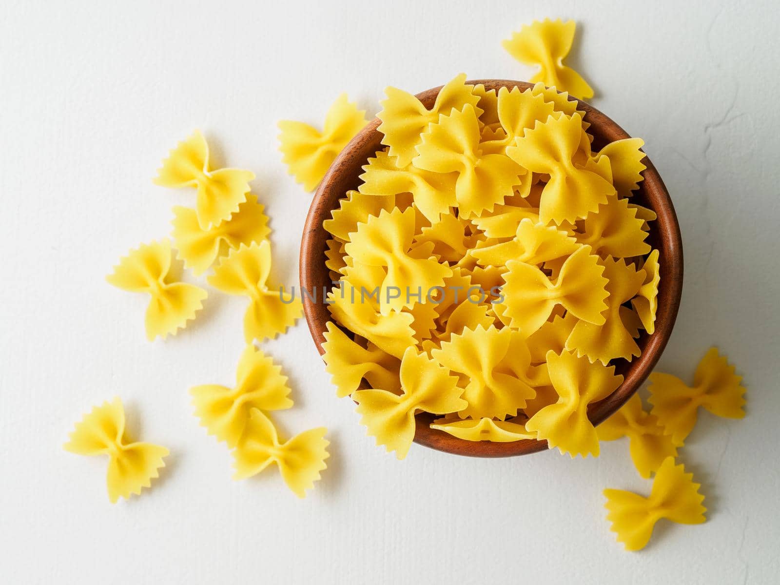 Pasta farfalle in wooden bowl on gray stone table. Top view, close up