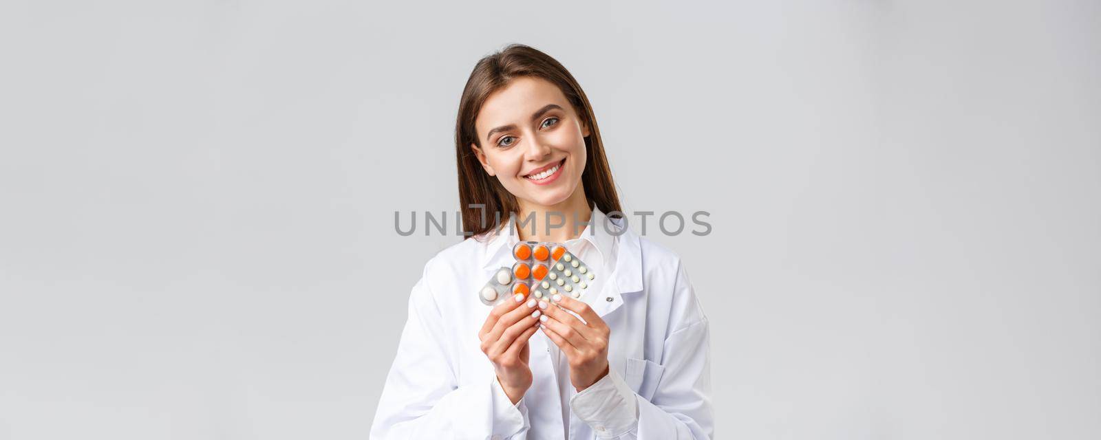 Pharmacy, healthcare workers, insurance and hospitals concept. Gorgeous doctor in white scrubs, female physician or pharmacist smiling, showing medicine, different pills or antibiotics.