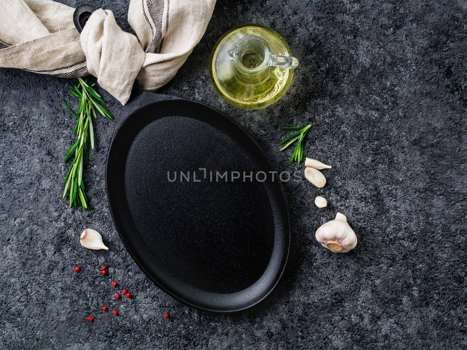 empty oval cast iron frying pan on dark grey concrete background, top view, blank space for text