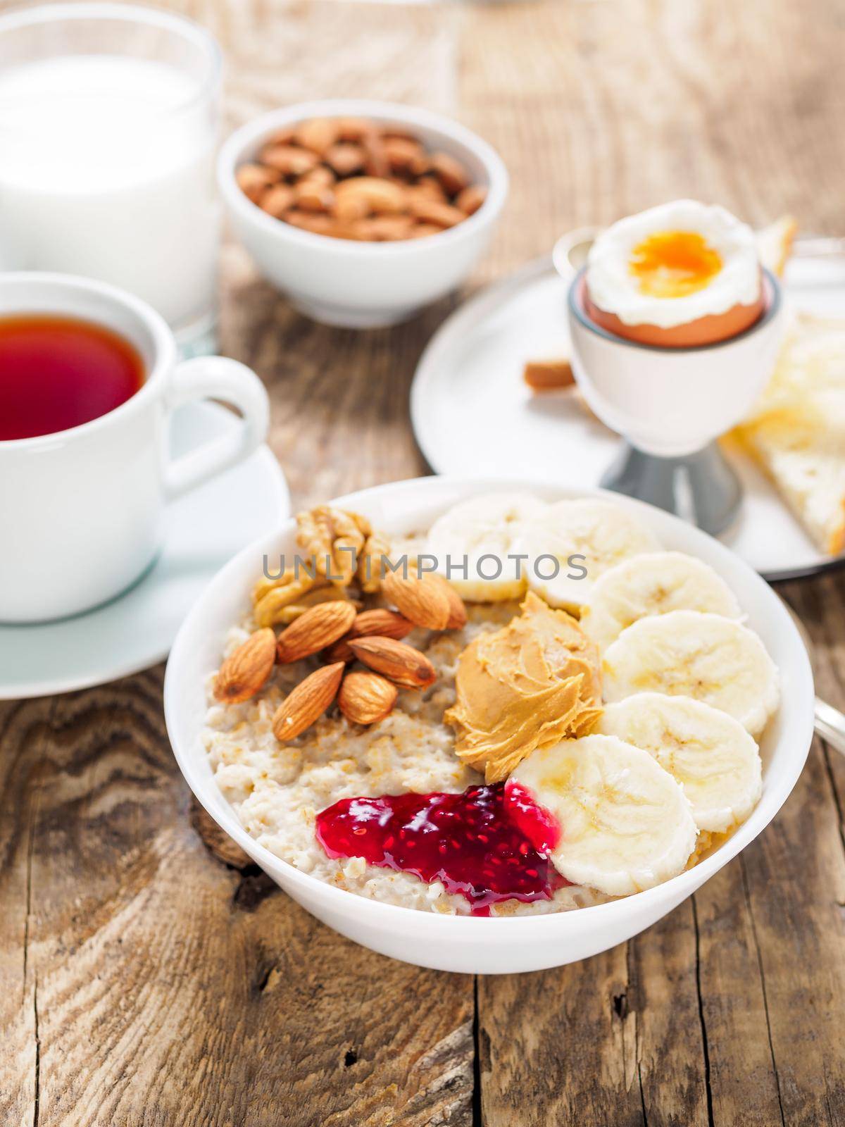 oatmeal with nuts and jam, soft boiled eggs, selective focus, side view, vertical frame by NataBene