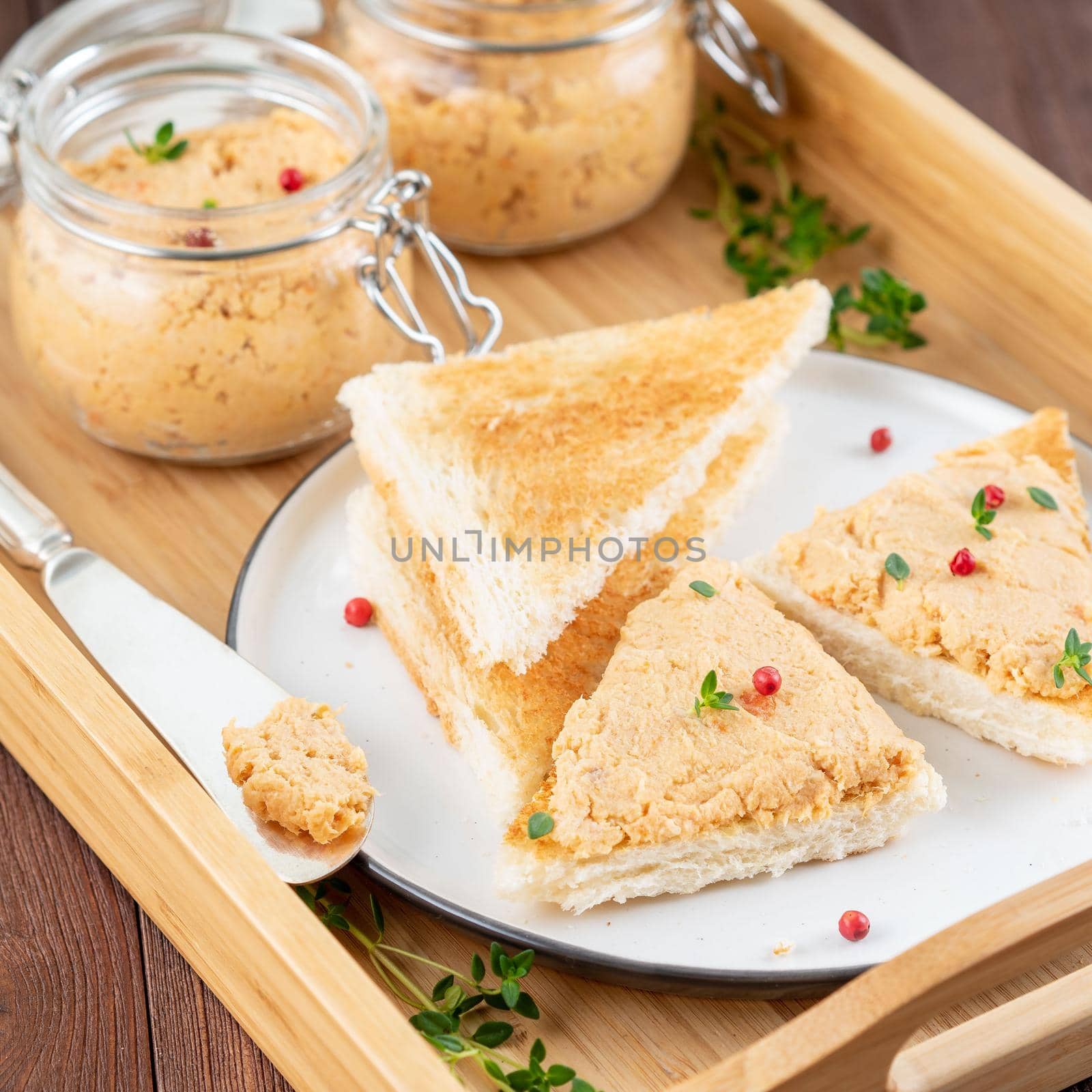 Fresh homemade chicken pate on toasted bread on tray over rustic background, side view by NataBene
