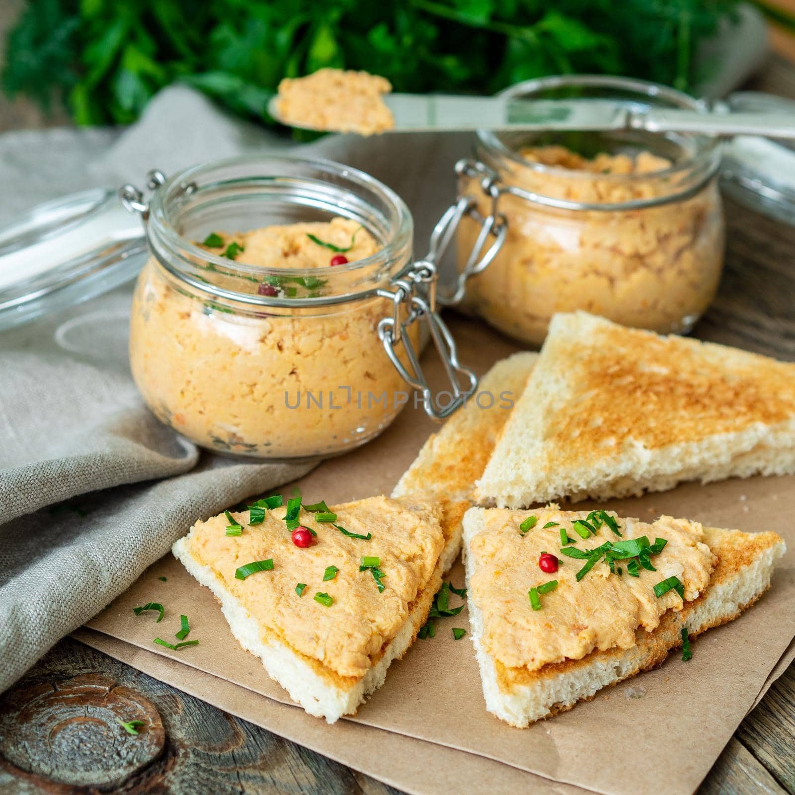 Fresh homemade chicken pate on a toasted bread over rustic background, side view