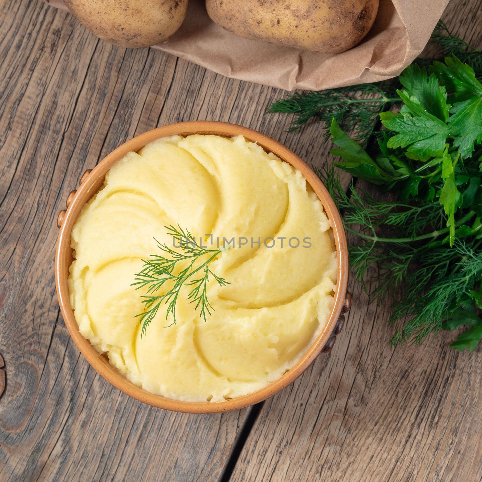 Mashed potatoes, boiled puree in a brown bowl on dark wooden rustic background, top view