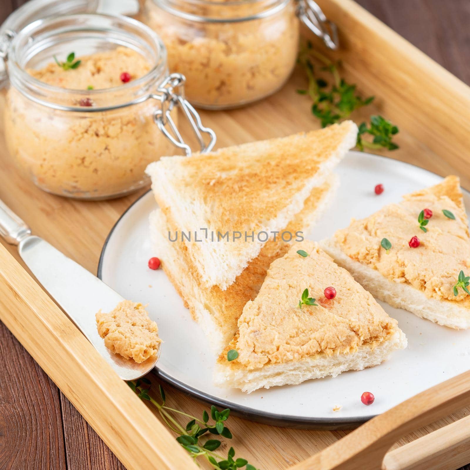 Fresh homemade chicken pate on toasted bread on tray over rustic background, side view by NataBene