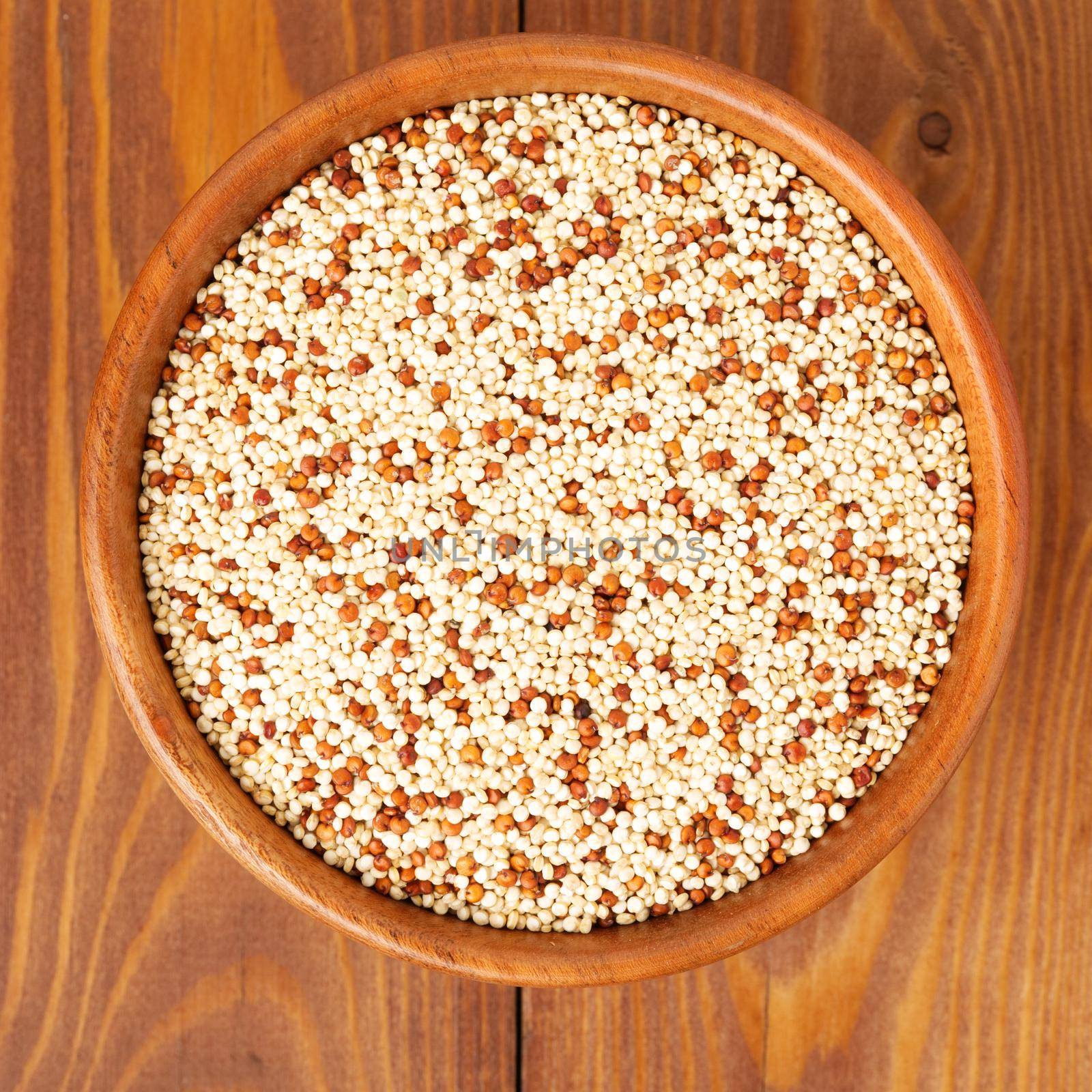 Raw Quinoa in a wooden bowl, superfood. Brown wooden background, top view.