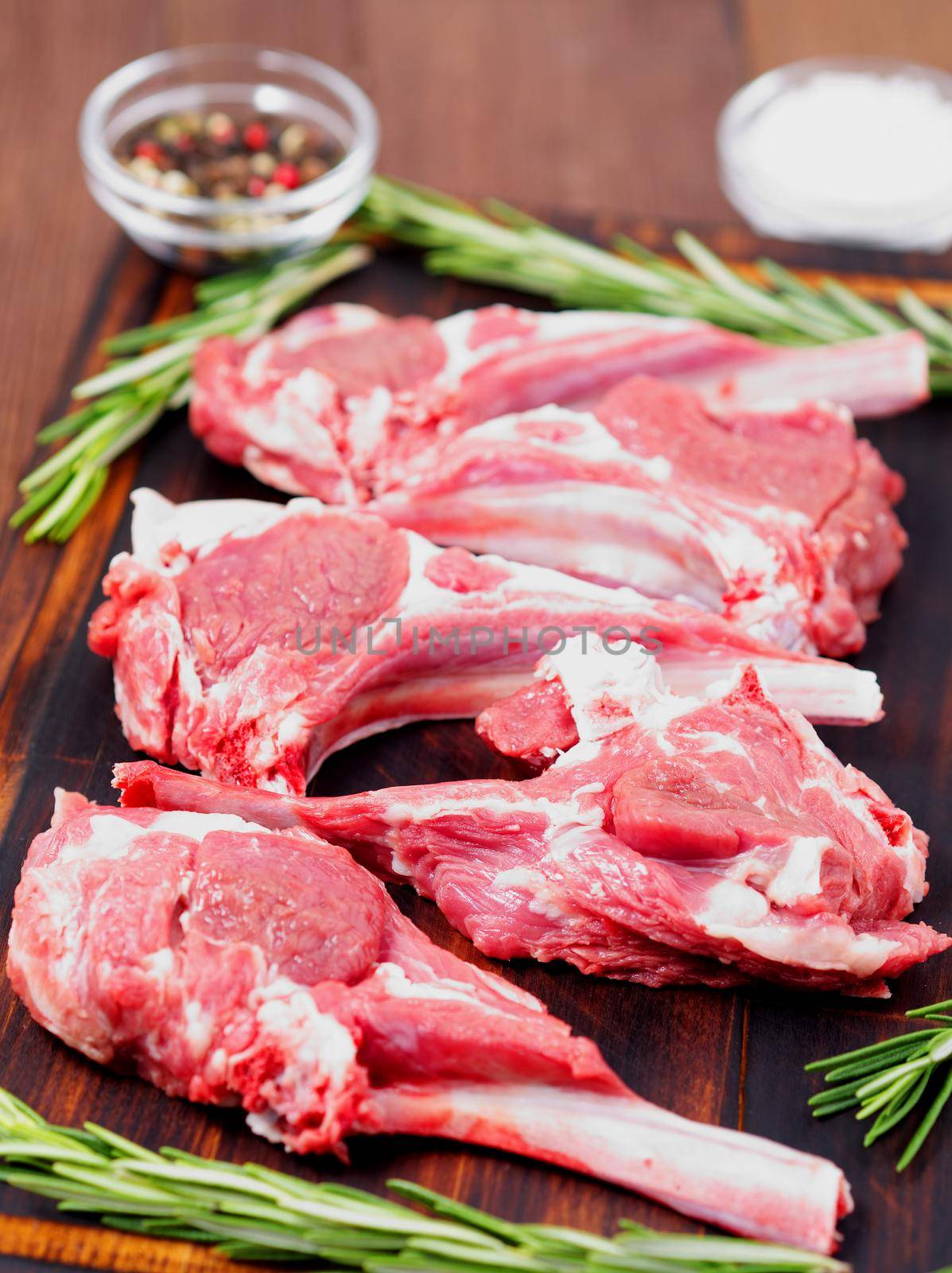 Raw lamb cutlets on bone on dark brown wooden background, lamb ribs, side view, vertical by NataBene