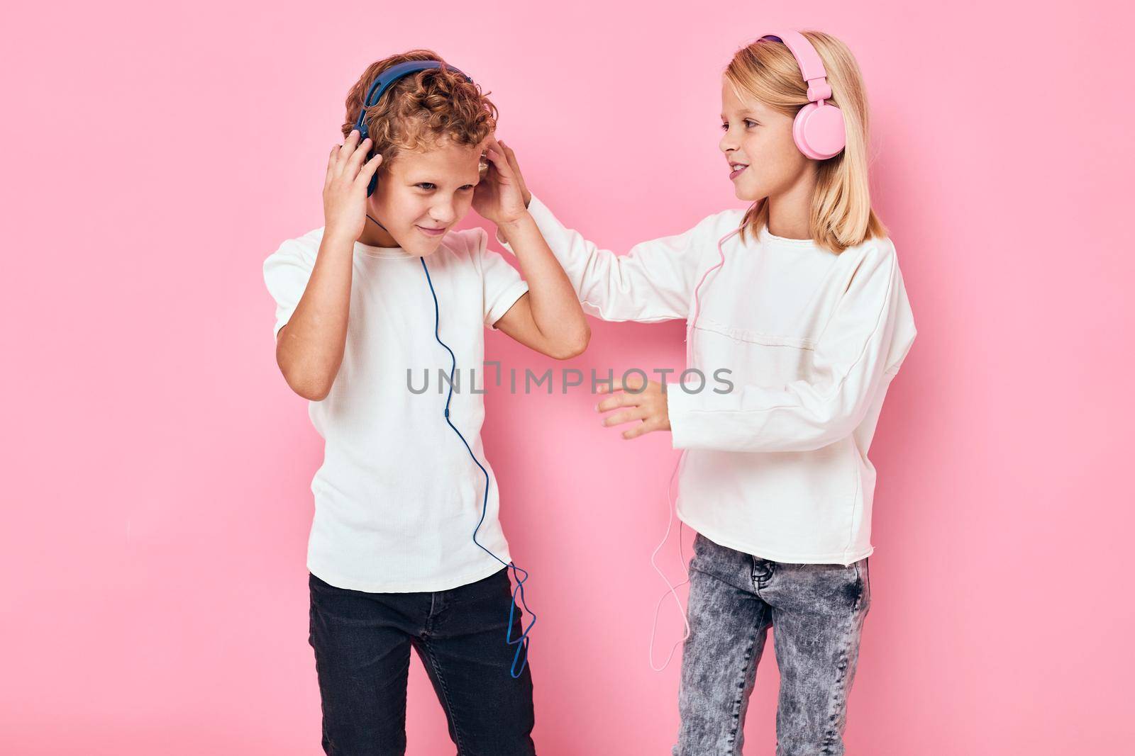boy and girl dancing with headphones entertainment pink color background. High quality photo