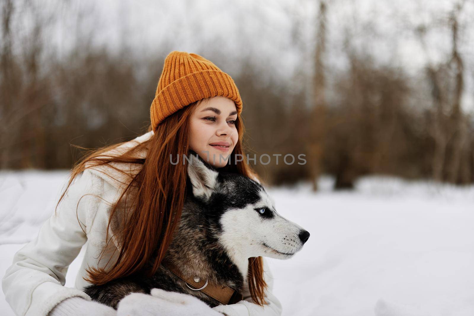 Happy young woman outdoors in a field in winter walking with a dog winter holidays by SHOTPRIME