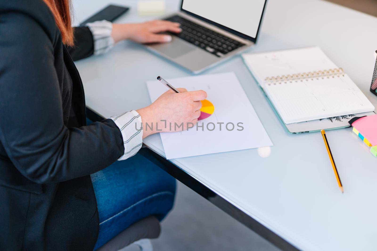 Young woman teleworking at home taking notes on laptop. by CatPhotography