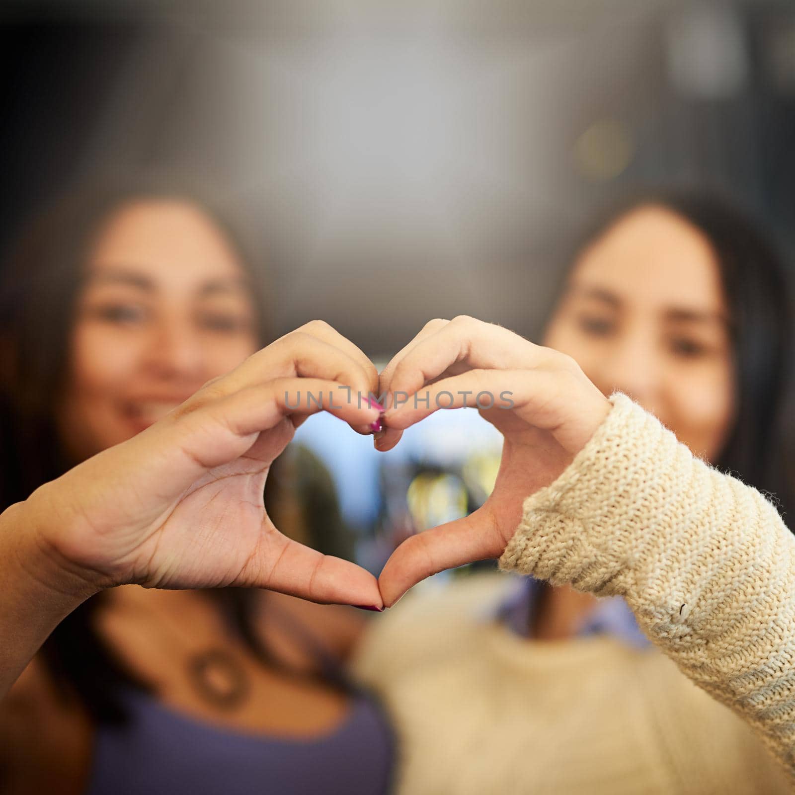 Portrait of two young friends making a heart shape with their hands.