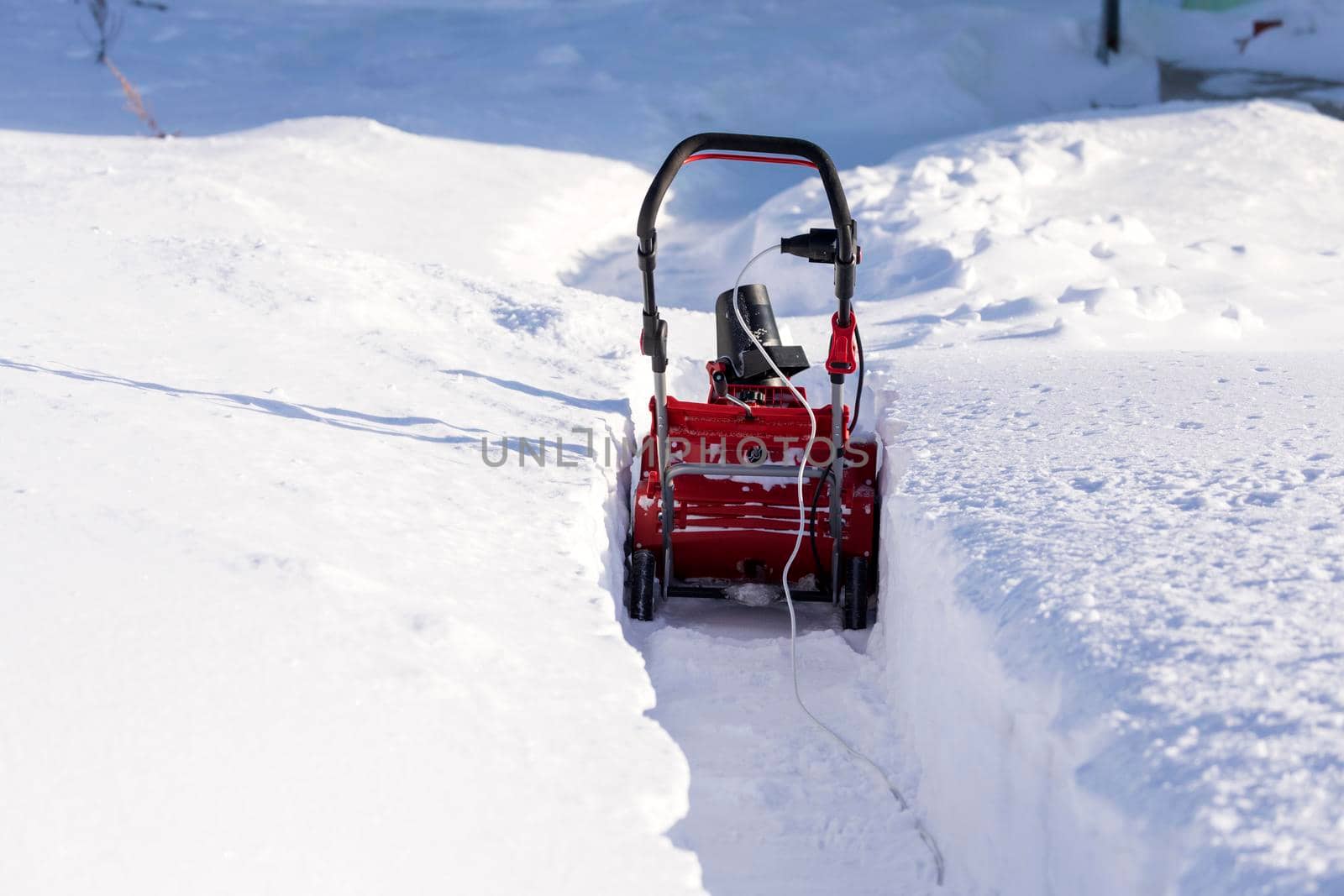 Cleaning the path from the snow with a snowplow on a winter day