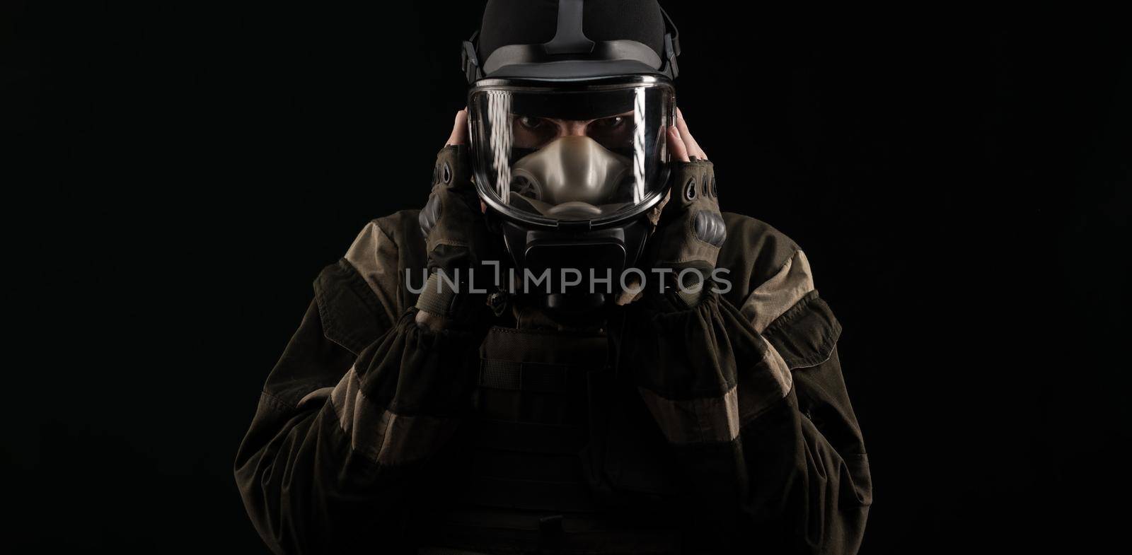 a man in a military uniform and a gas mask holds with an angry expression of emotions on a black background by Rotozey