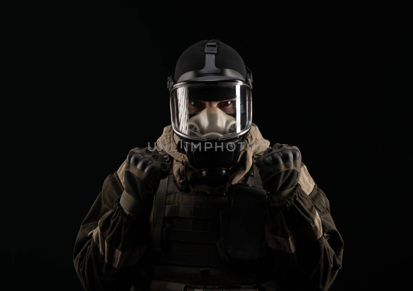 a man in a military uniform and a gas mask holds with an angry expression of emotions on a black background by Rotozey