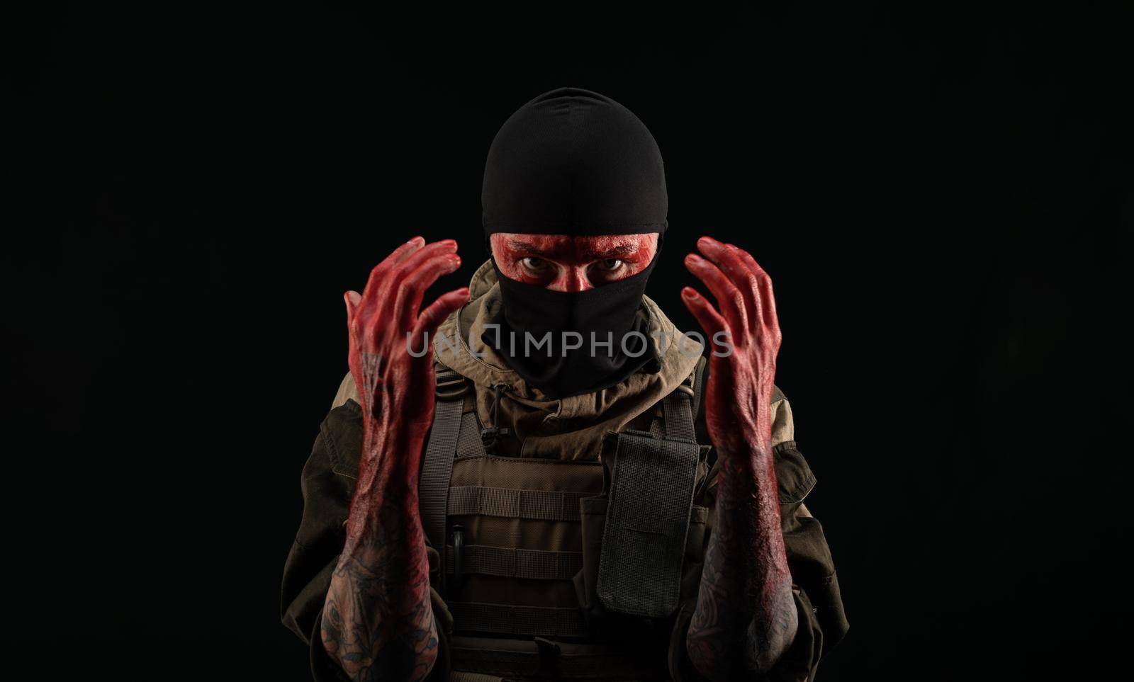 photo of a man in a military uniform and balaclava with a bloody face and hands up to the elbow in blood on a black background by Rotozey