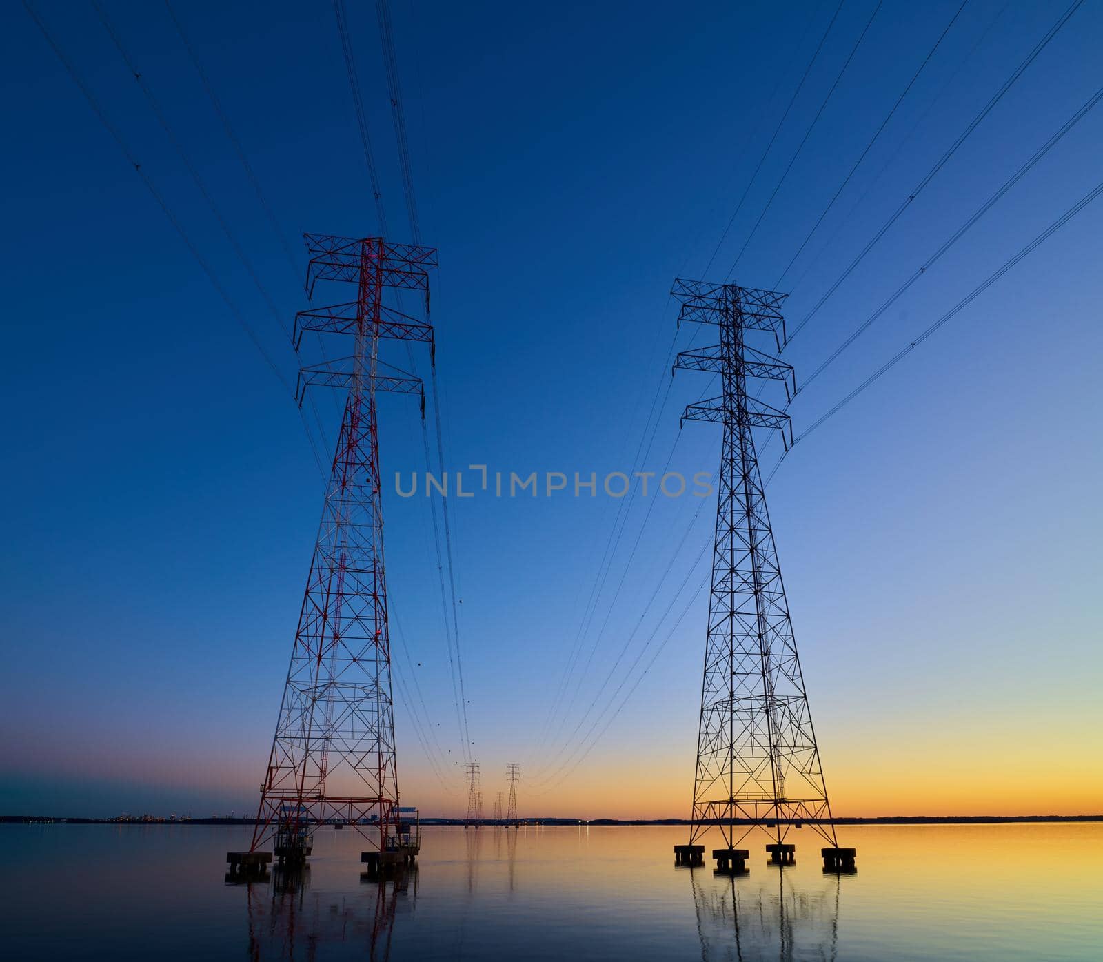 High voltage transmission lines crossing Wheeler Lake at dusk near Athens AL. Electricity pylons at sunset. Power and energy. by patrickstock