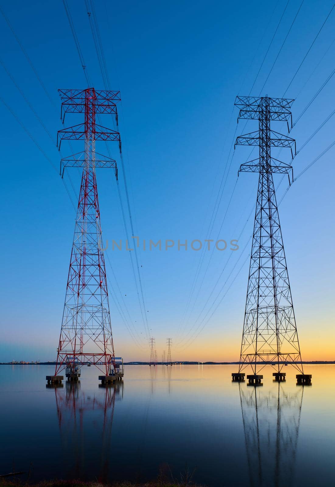 High voltage transmission lines crossing Wheeler Lake at dusk near Athens AL. Electricity pylons at sunset. Power and energy.